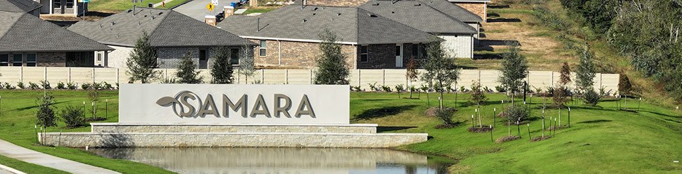 Stone monument sign reading 'SAMARA' beside a small pond with homes in the background.