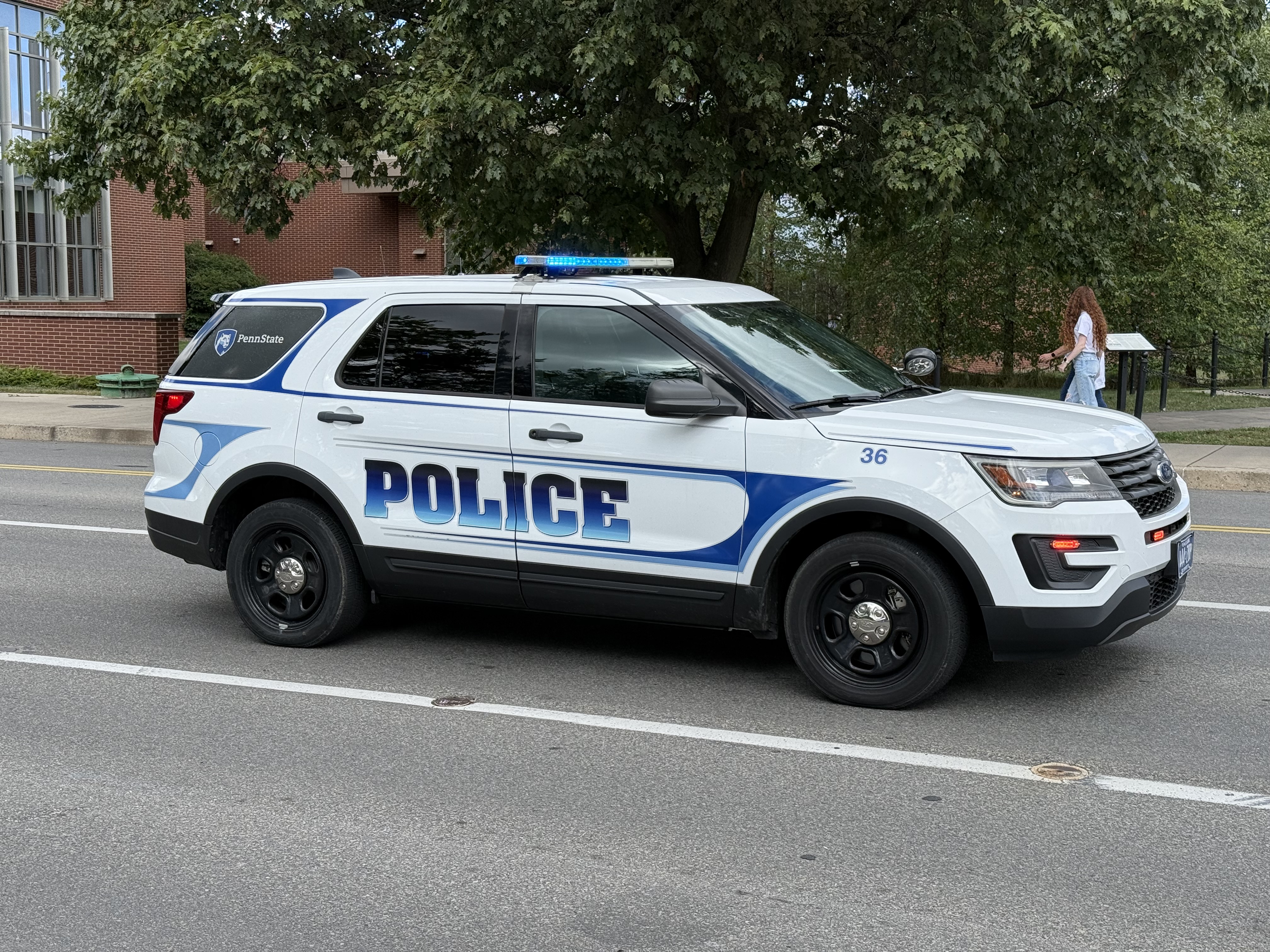 A white police SUV with emergency lights parked on a street near a building.