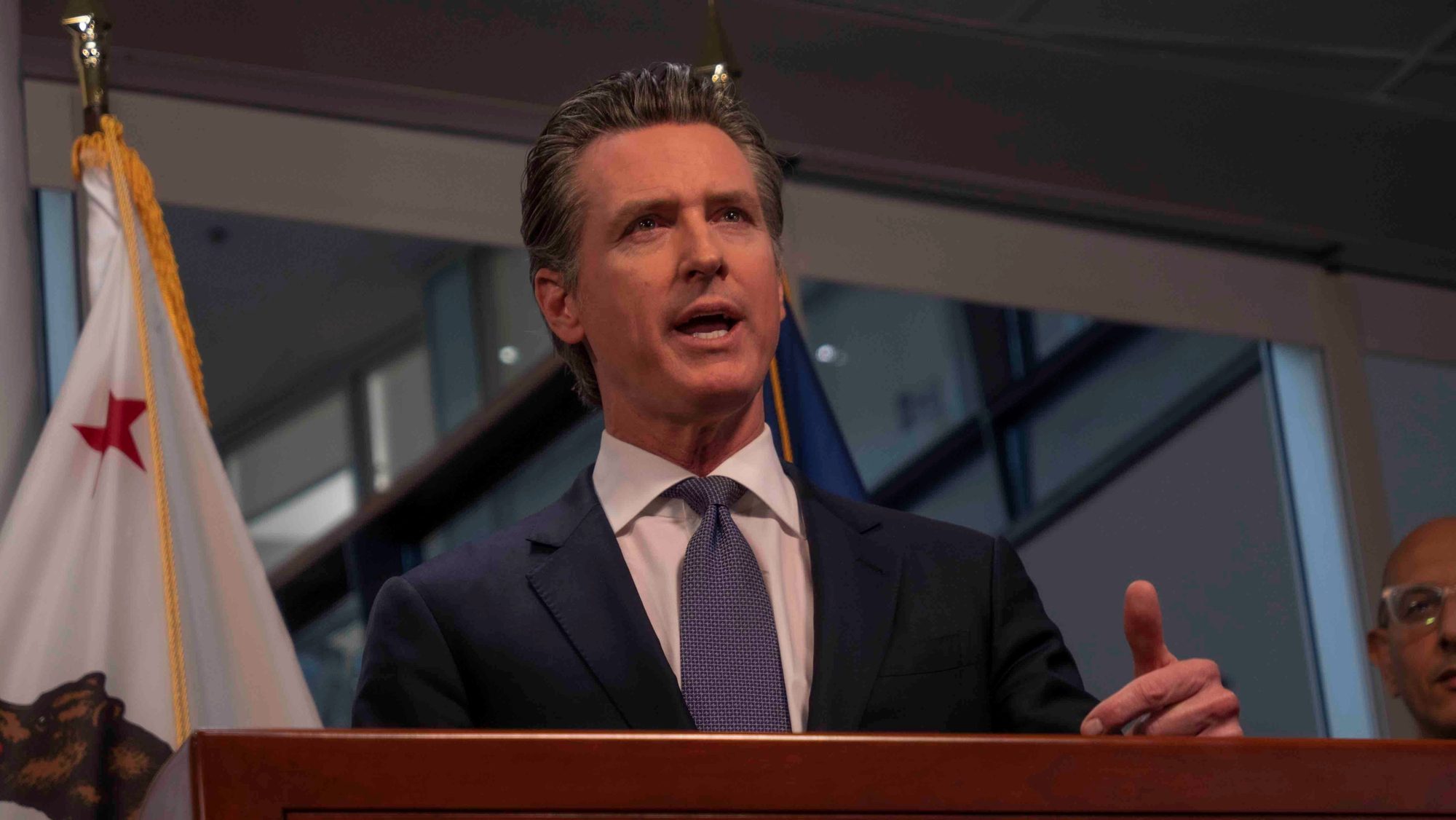 Gavin Newsom speaking at a podium in Sacramento.