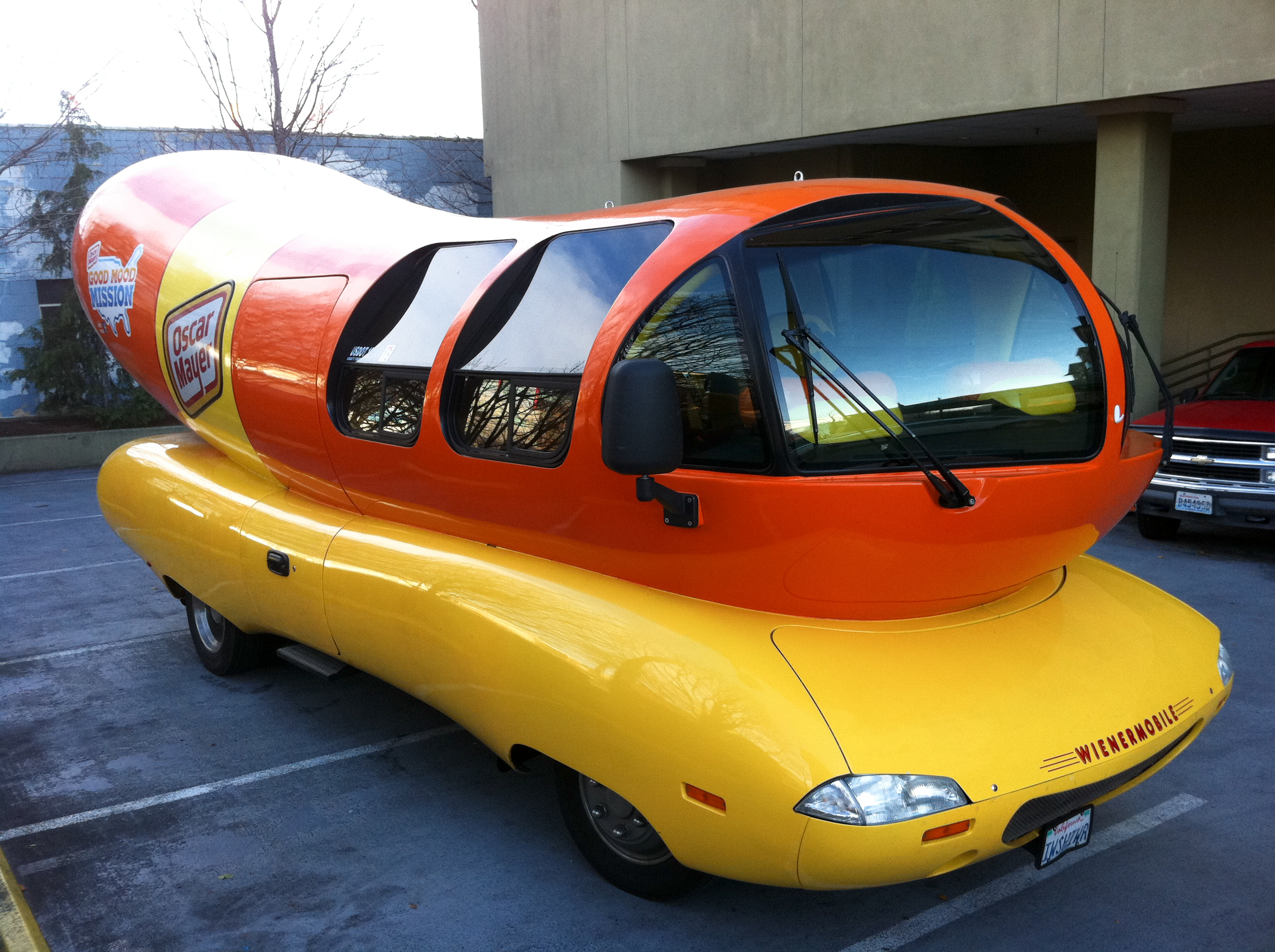 The Oscar Mayer Wienermobile, a large hot-dog-shaped vehicle, parked in a surface lot.