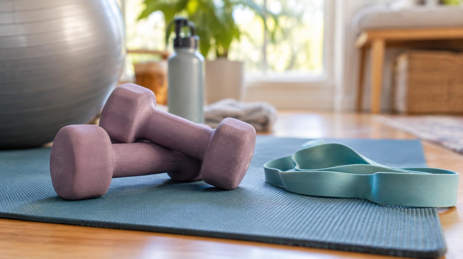 Light dumbbells and a resistance band resting on a yoga mat.