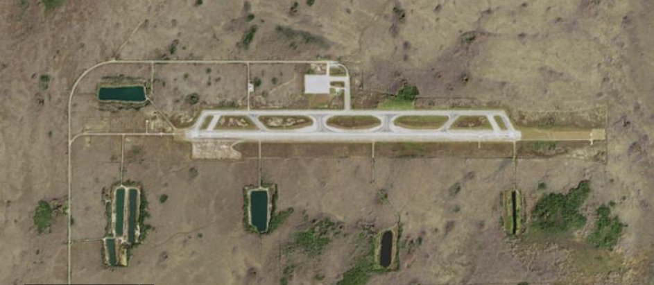 Satellite aerial view of a small airport runway surrounded by scrubland and wetlands.