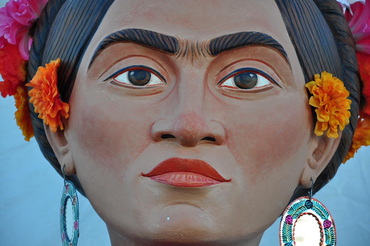 Close-up of a painted Frida Kahlo figure with flowers in her hair and large decorative earrings.
