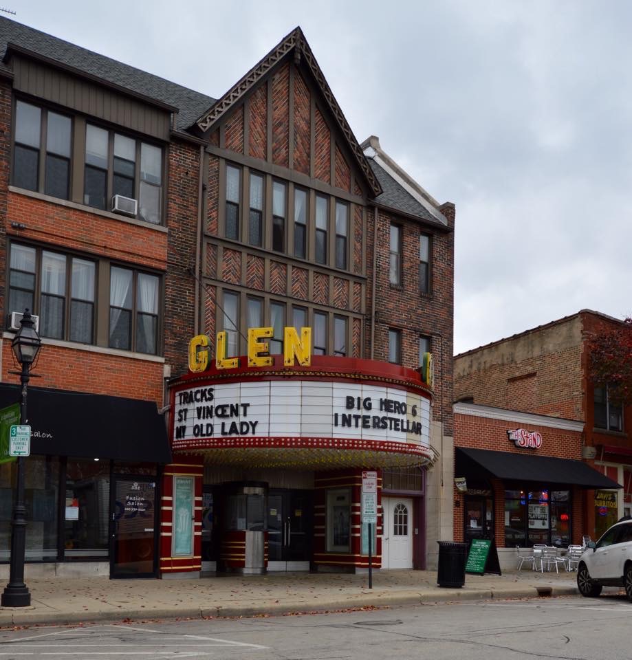 Brick theater building with marquee on a downtown commercial street with neighboring storefronts.