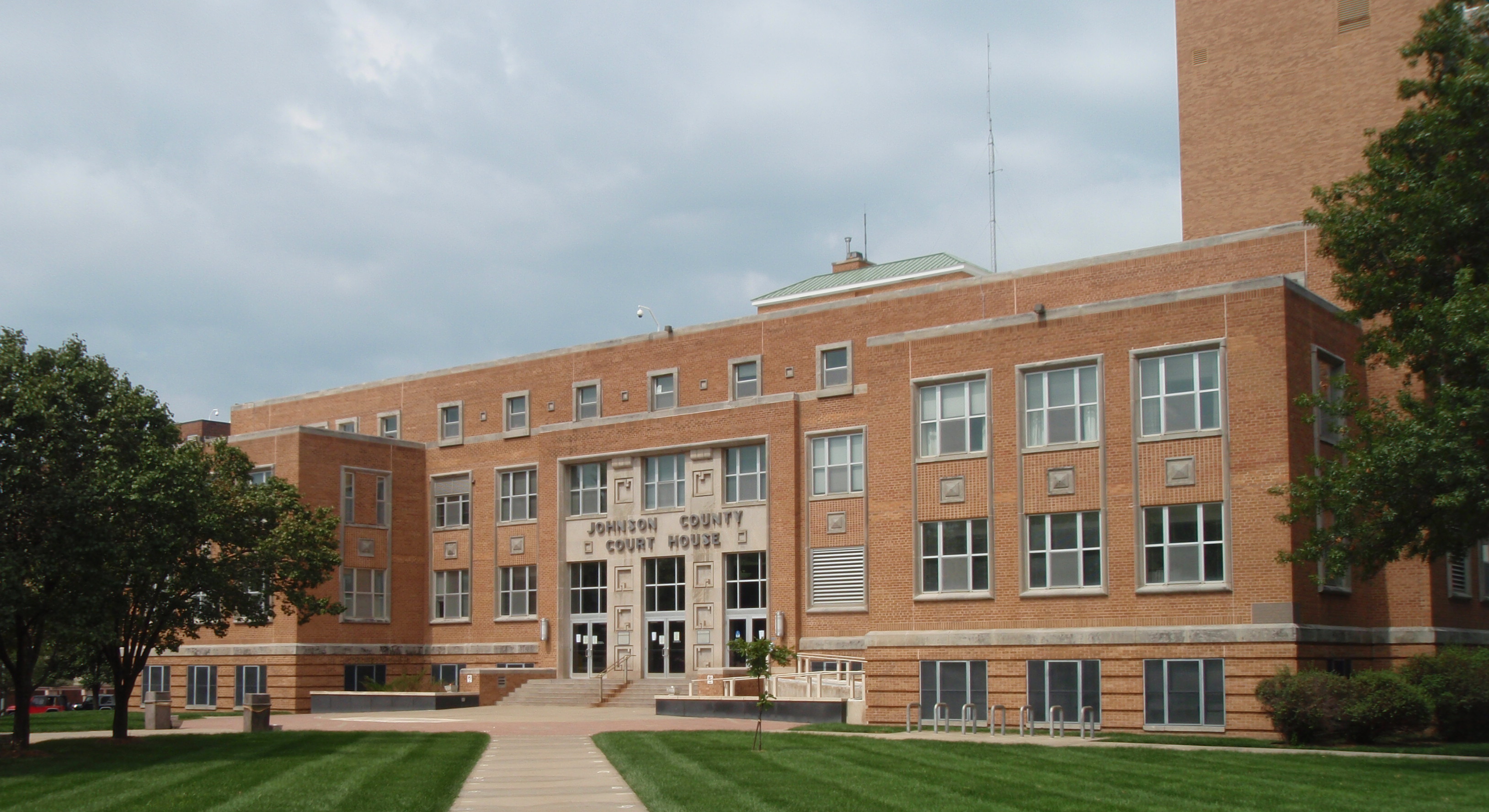 Red brick multi-story courthouse building with central entrance and manicured lawn.