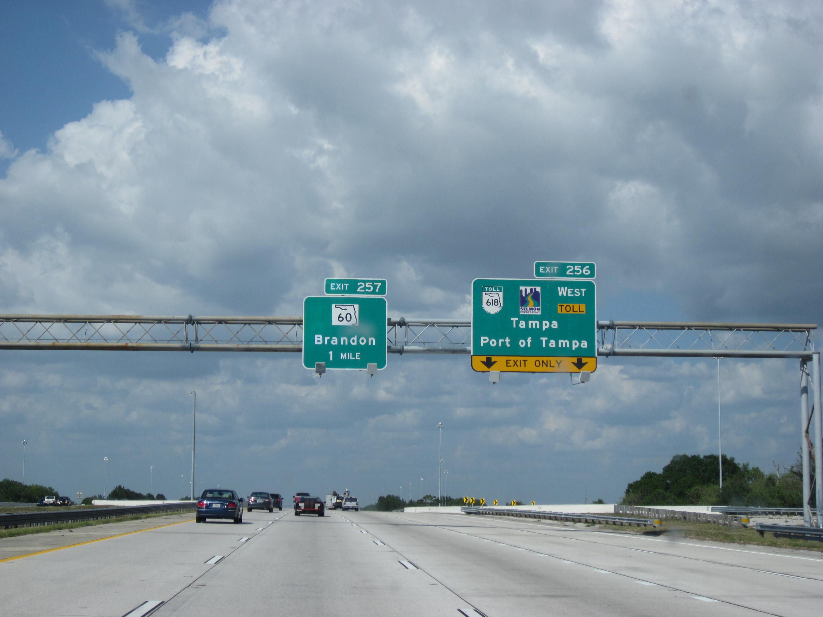Multi-lane Florida interstate highway with overhead green exit signs and vehicles.