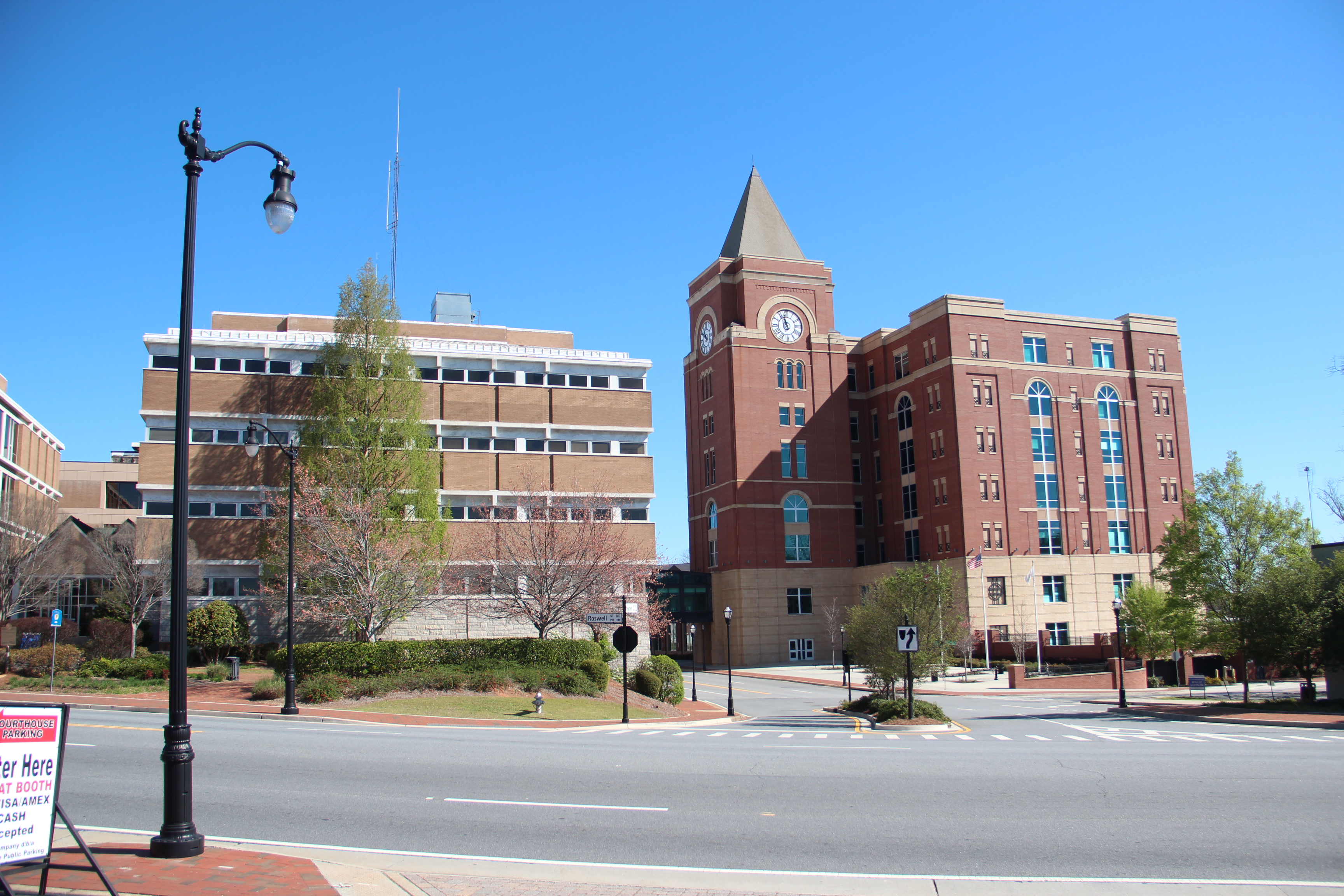 Red brick courthouse complex with a prominent clock tower under a clear blue sky.