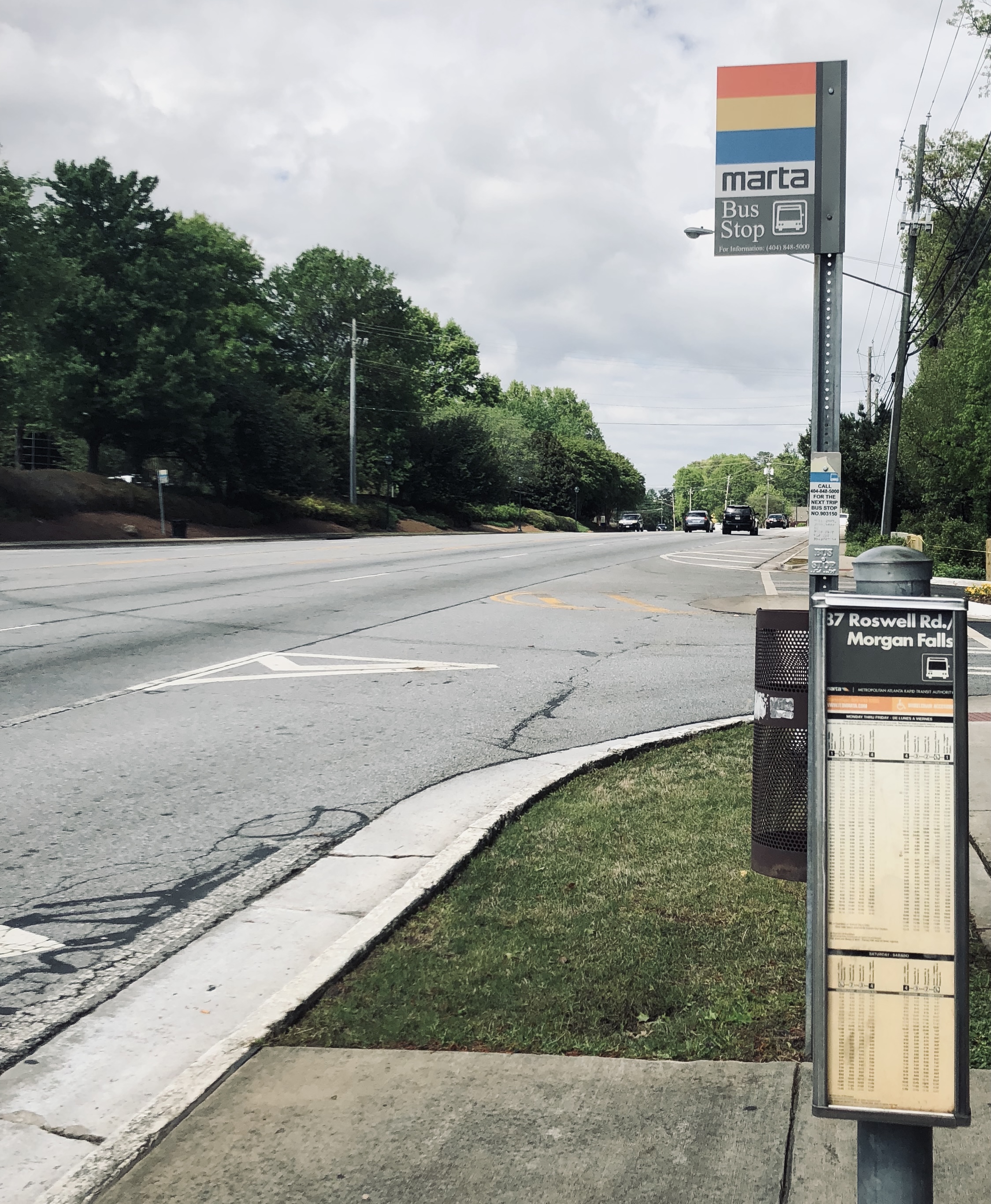 MARTA bus stop sign on a pole along a multi-lane suburban road.