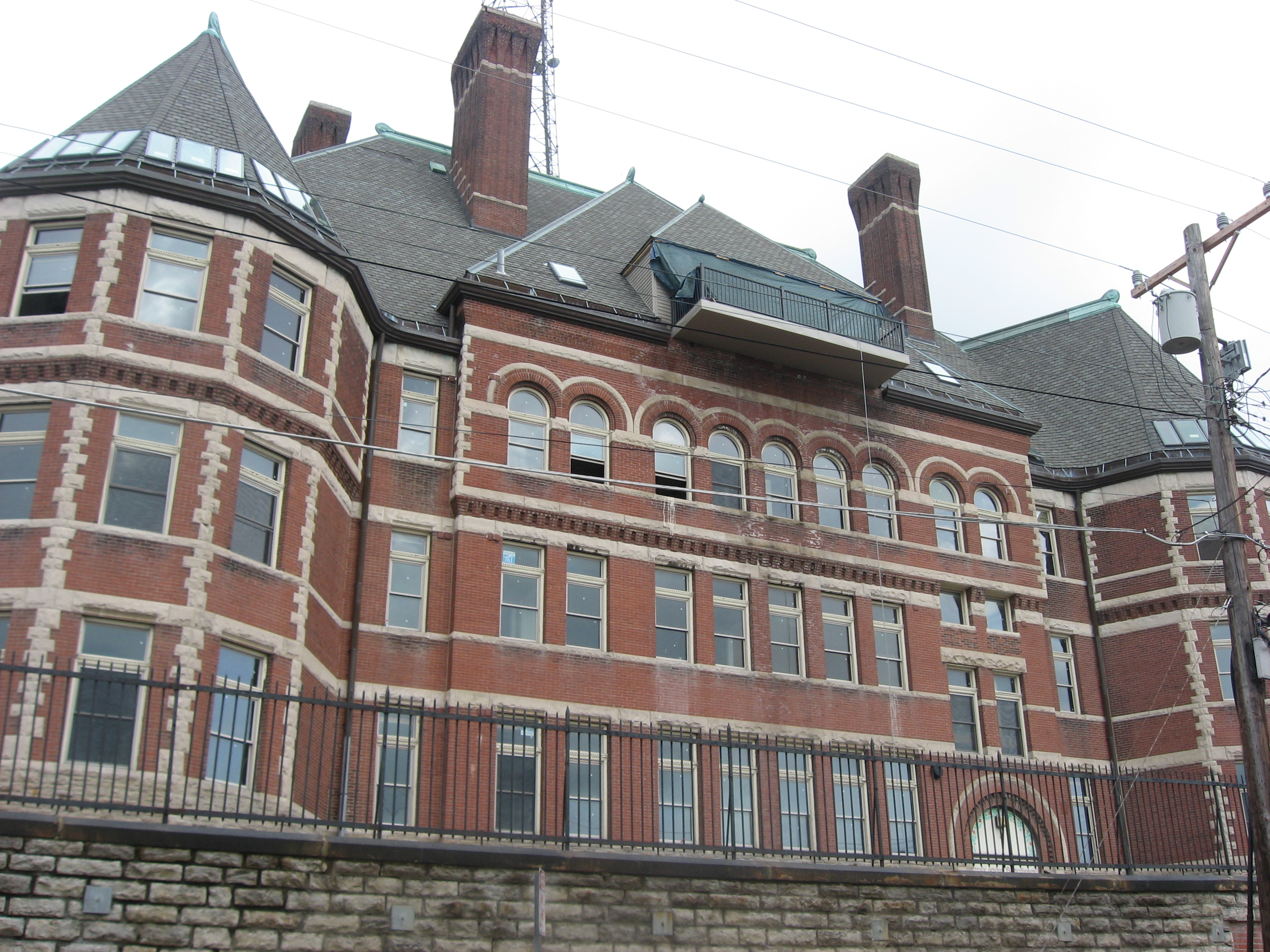 Large historic red-brick Victorian school building with arched windows and metal fence.