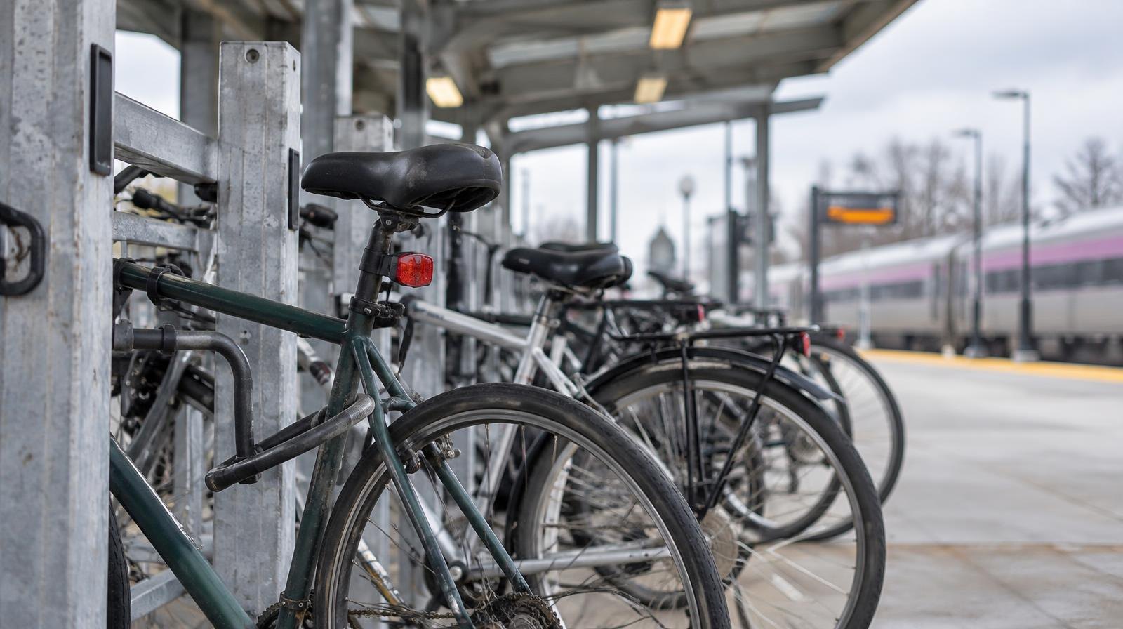 Bicycles locked in a modern outdoor bike parking station with steel framing above.