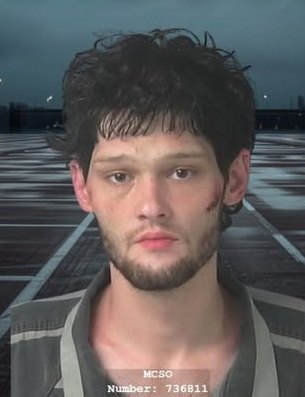 Law enforcement booking photo of a young man in a gray jail garment.