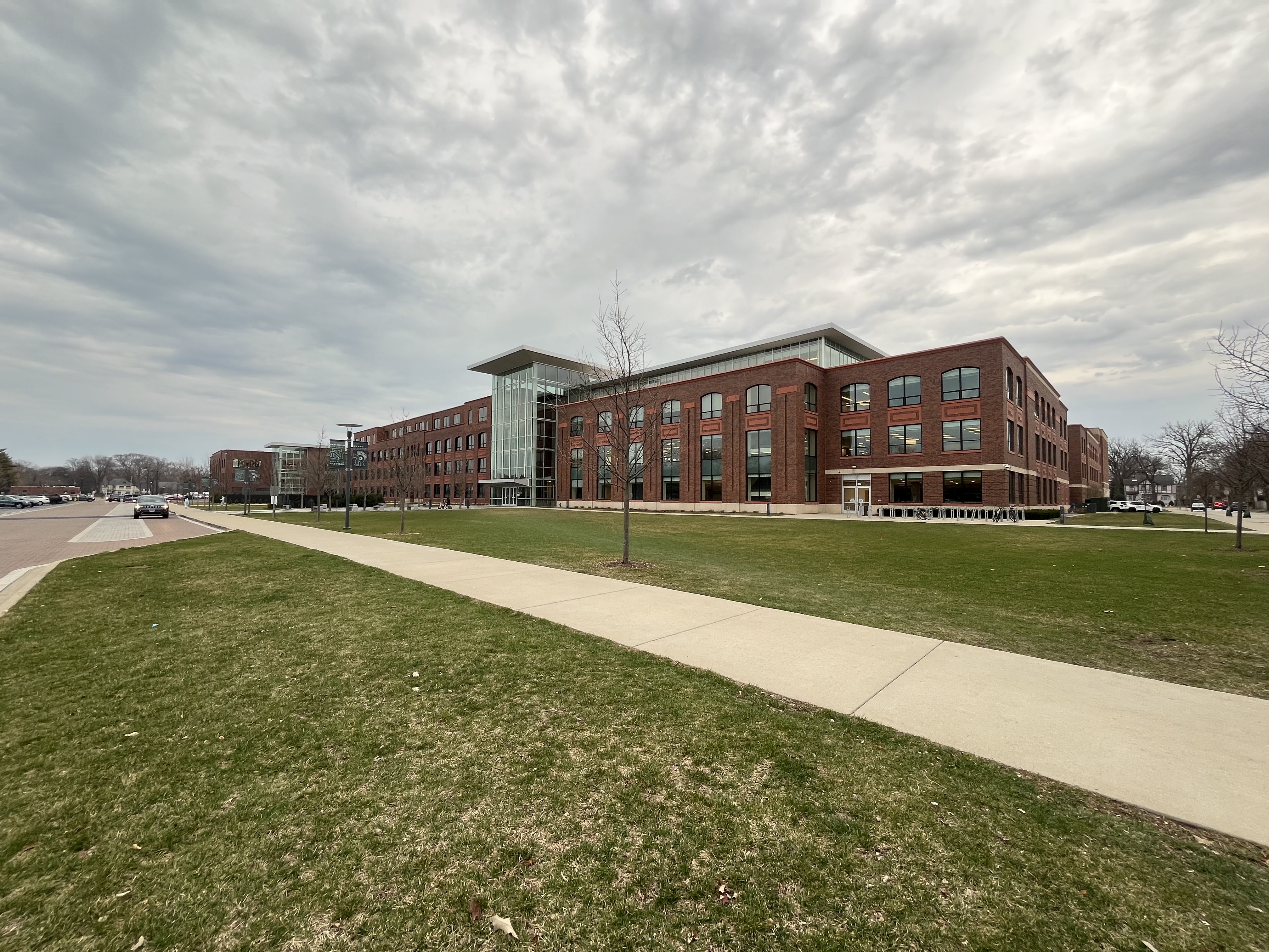 Large multi-story red brick school building with a glass entrance under an overcast sky.