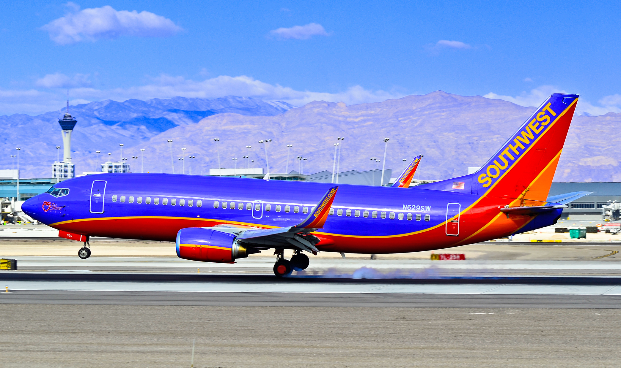 A Southwest Airlines Boeing 737 in blue and red livery on an airport tarmac with mountains behind.