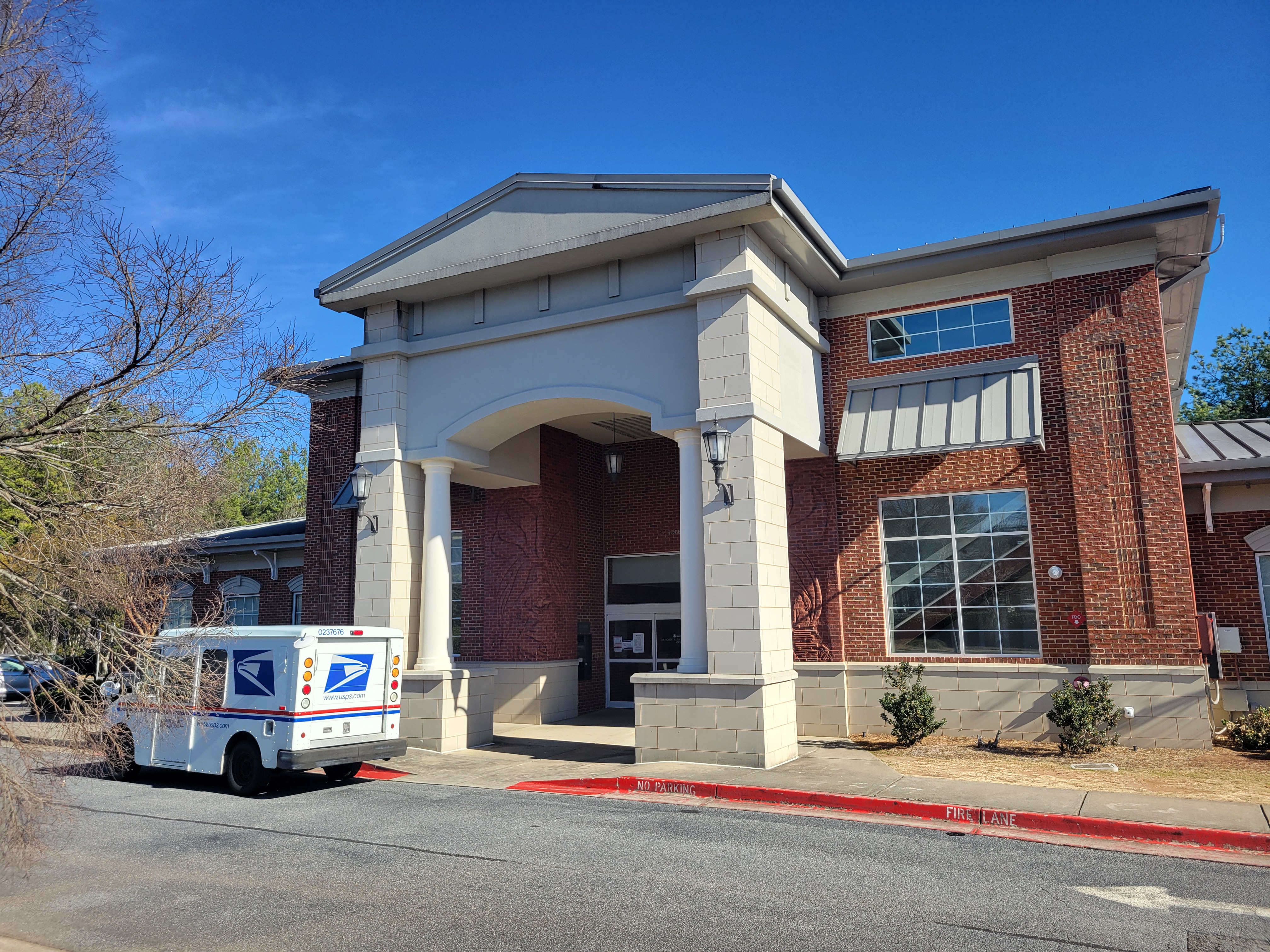 Brick public library building with a large arched entrance and white columns.