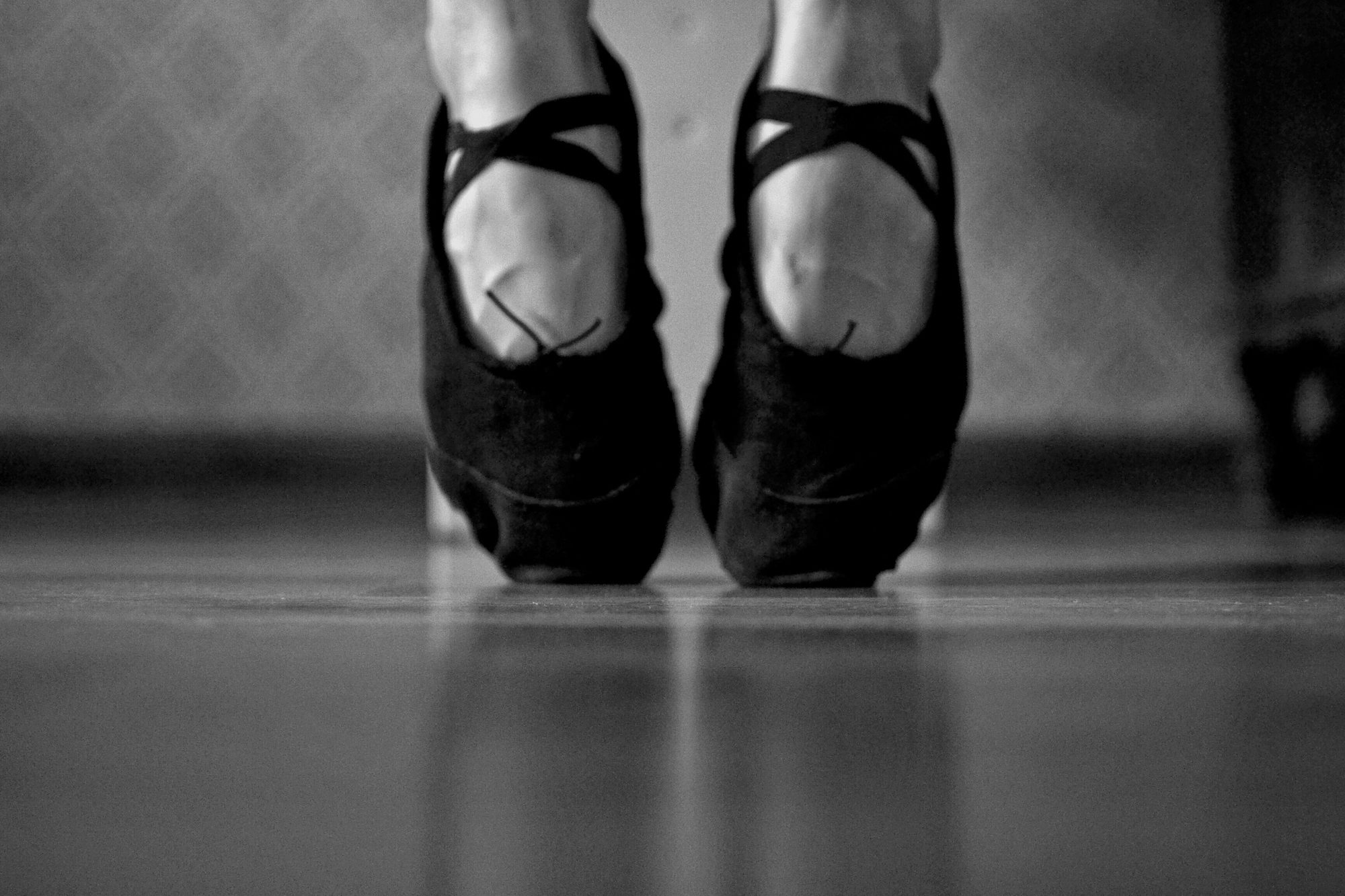 Artistic black and white photo of a ballerina's feet on pointe shoes.