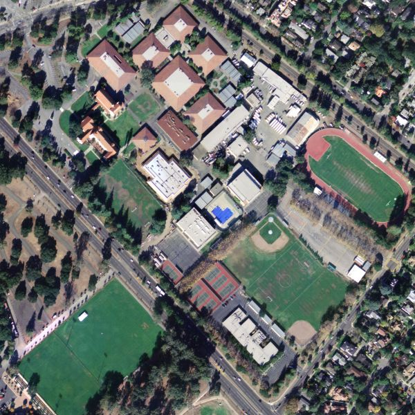 Aerial view of a large school campus with a running track, athletic fields, and multiple buildings.
