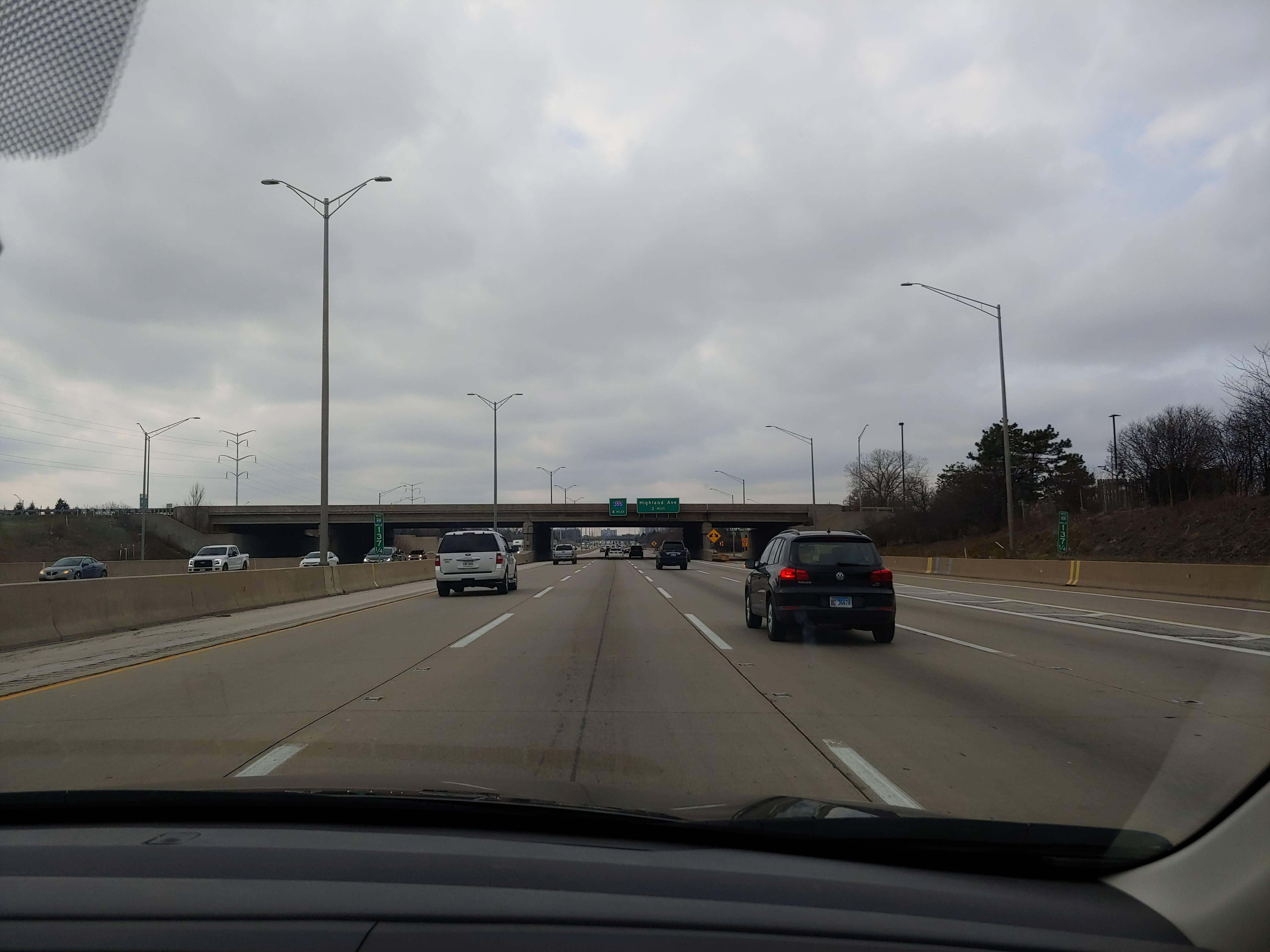 Westbound highway traffic on I-88 passing under an overpass on a cloudy day.