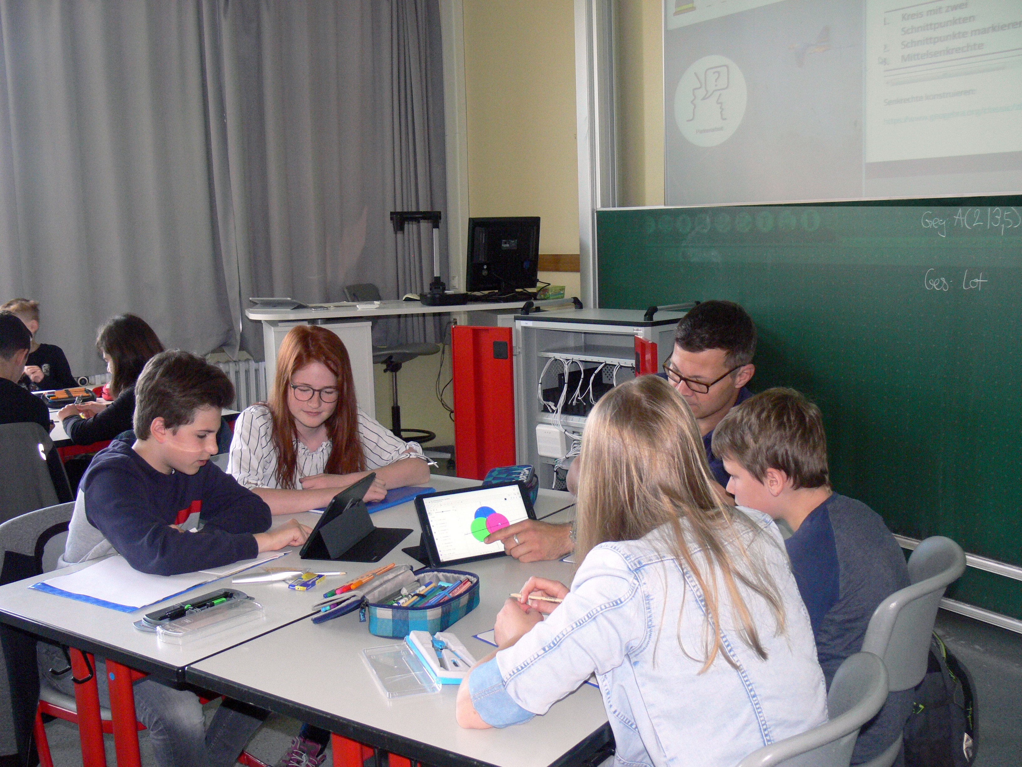 Students using tablet devices during a math and geometry lesson in a classroom.