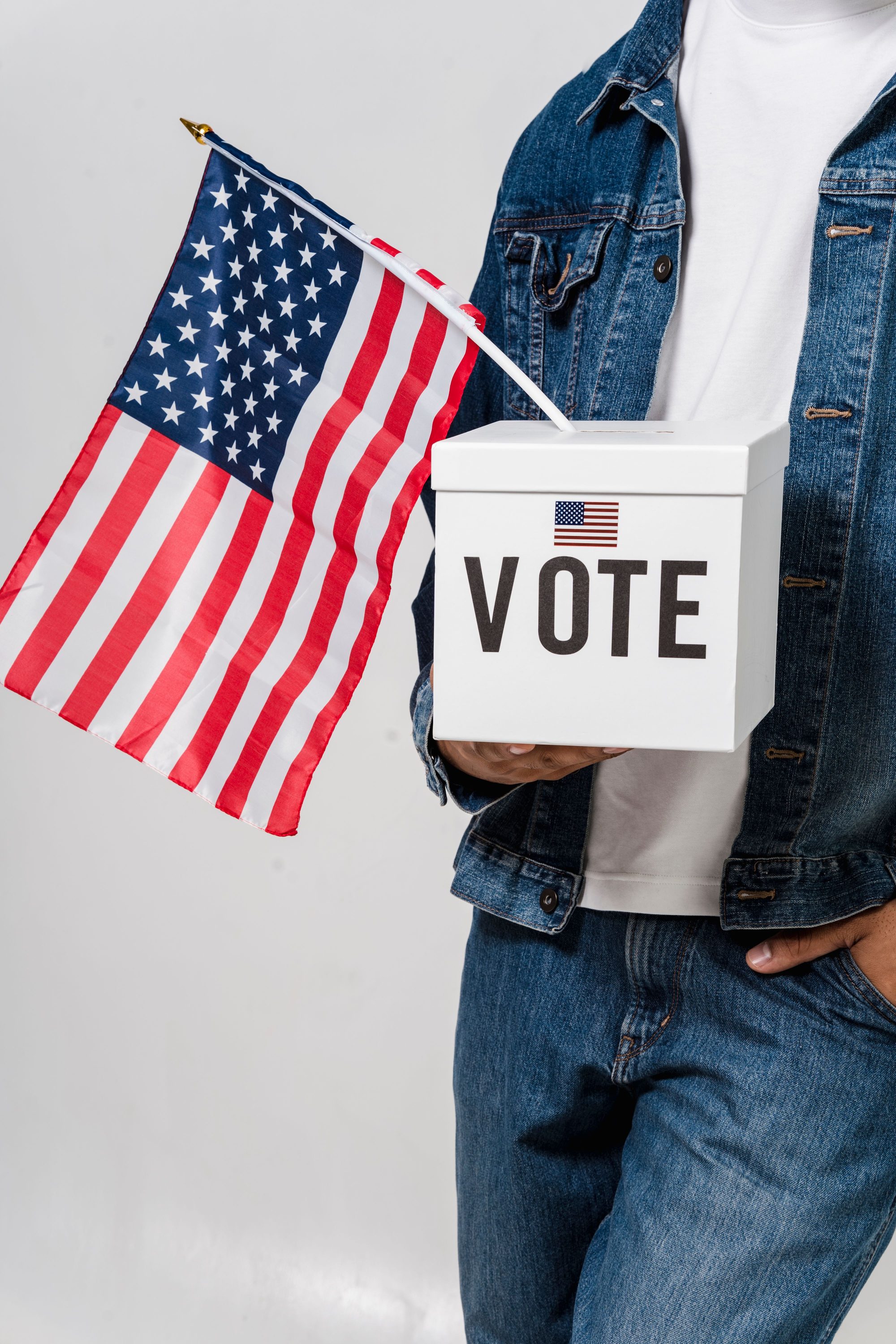 Person holding a ballot box and American flag, symbolizing voting and democracy.