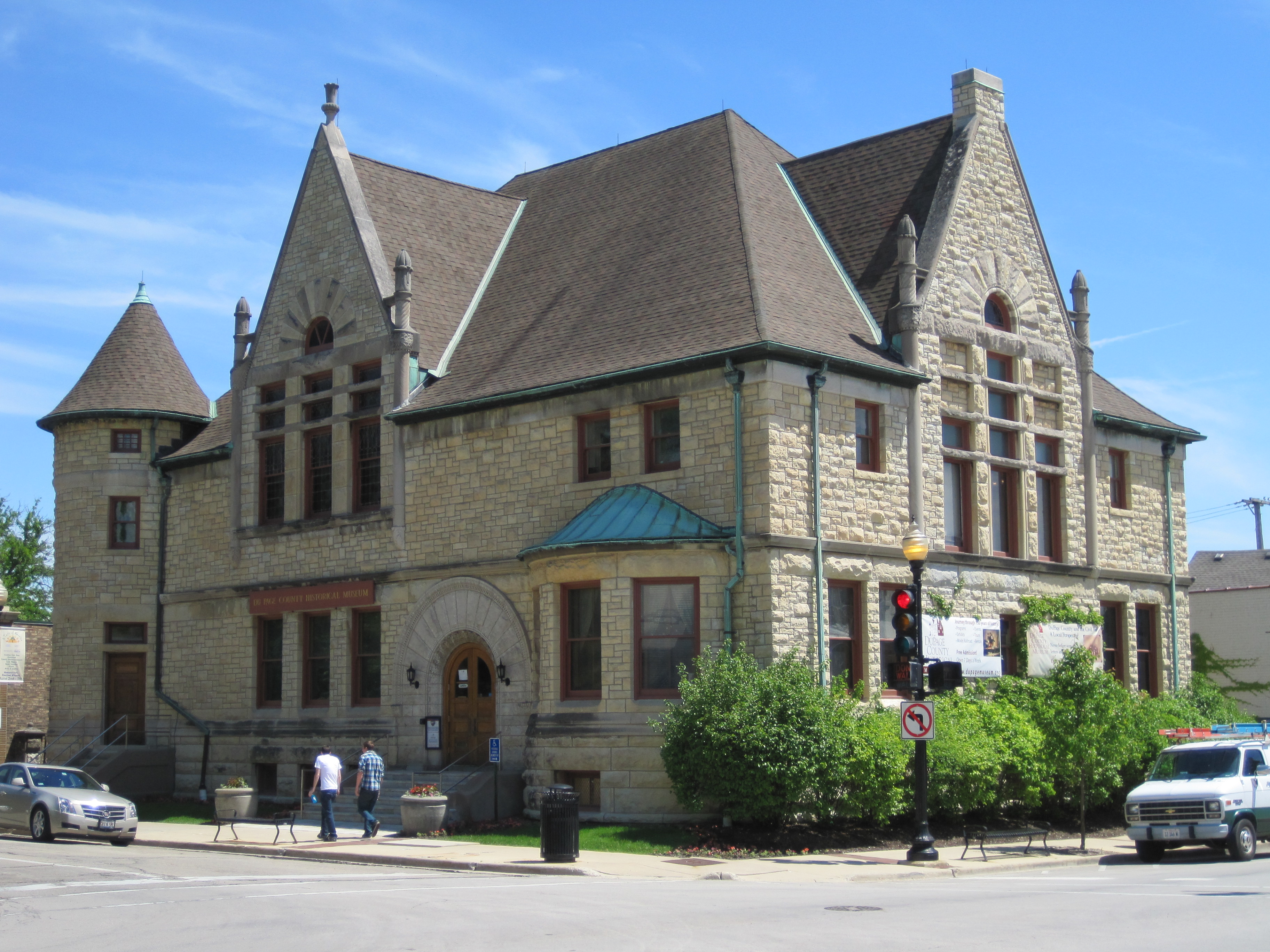Gothic Revival stone building with pointed gables and a corner turret on a street corner.