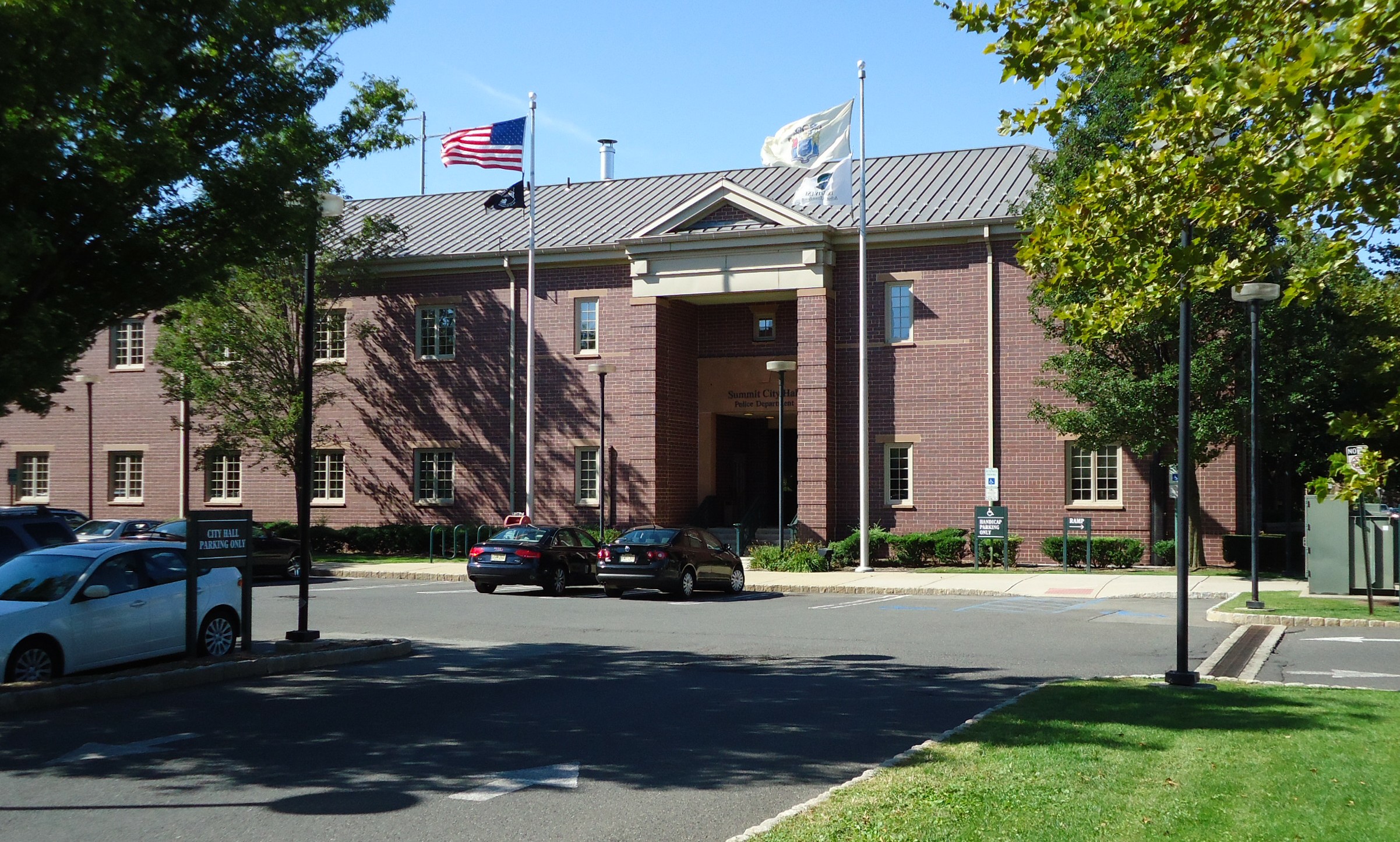 Brick city hall building in Summit, New Jersey, viewed from the parking lot on a clear day.