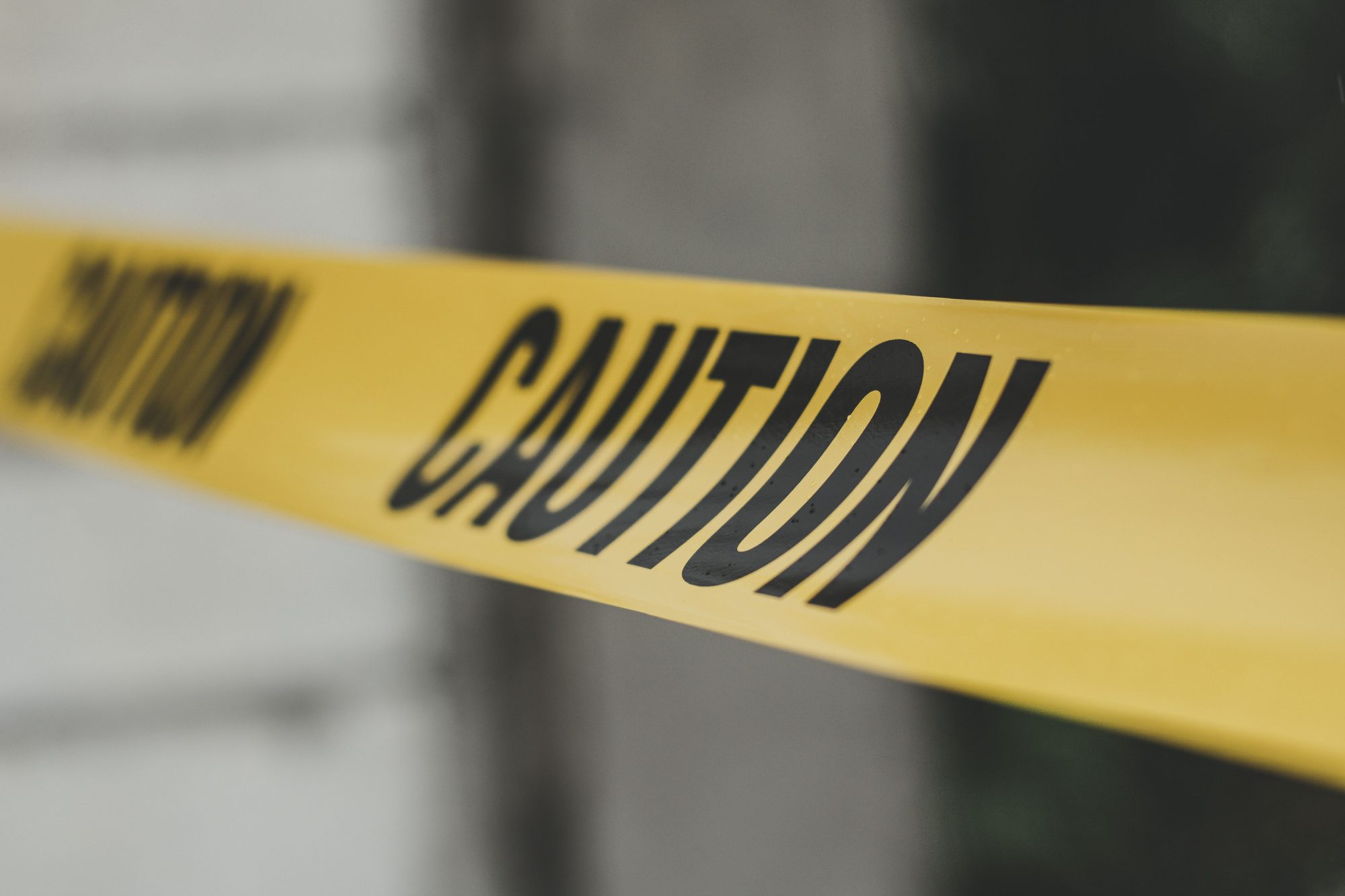 Close-up image of yellow caution tape with blurred background, emphasizing warning and safety.