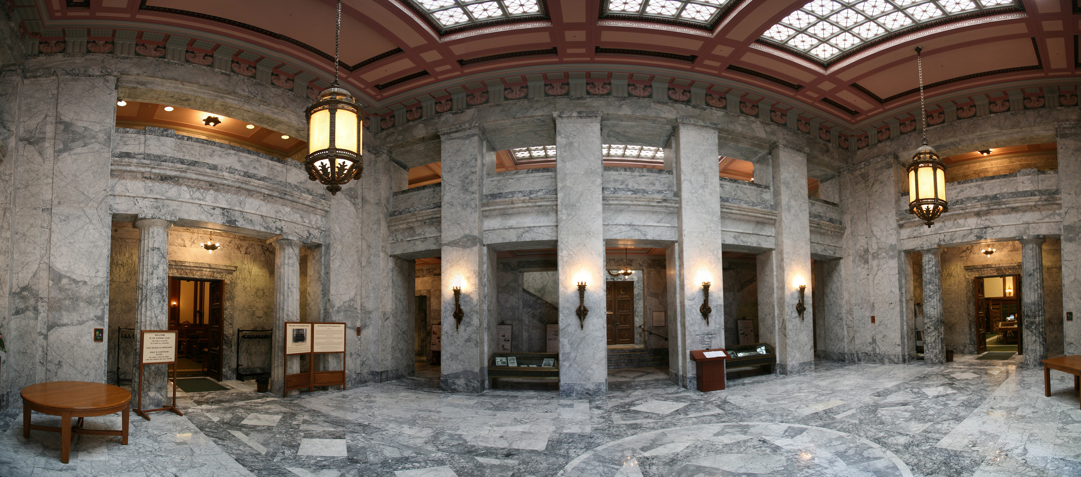 Grand marble interior lobby with tall columns, ornate ceiling, and hanging lantern fixtures.