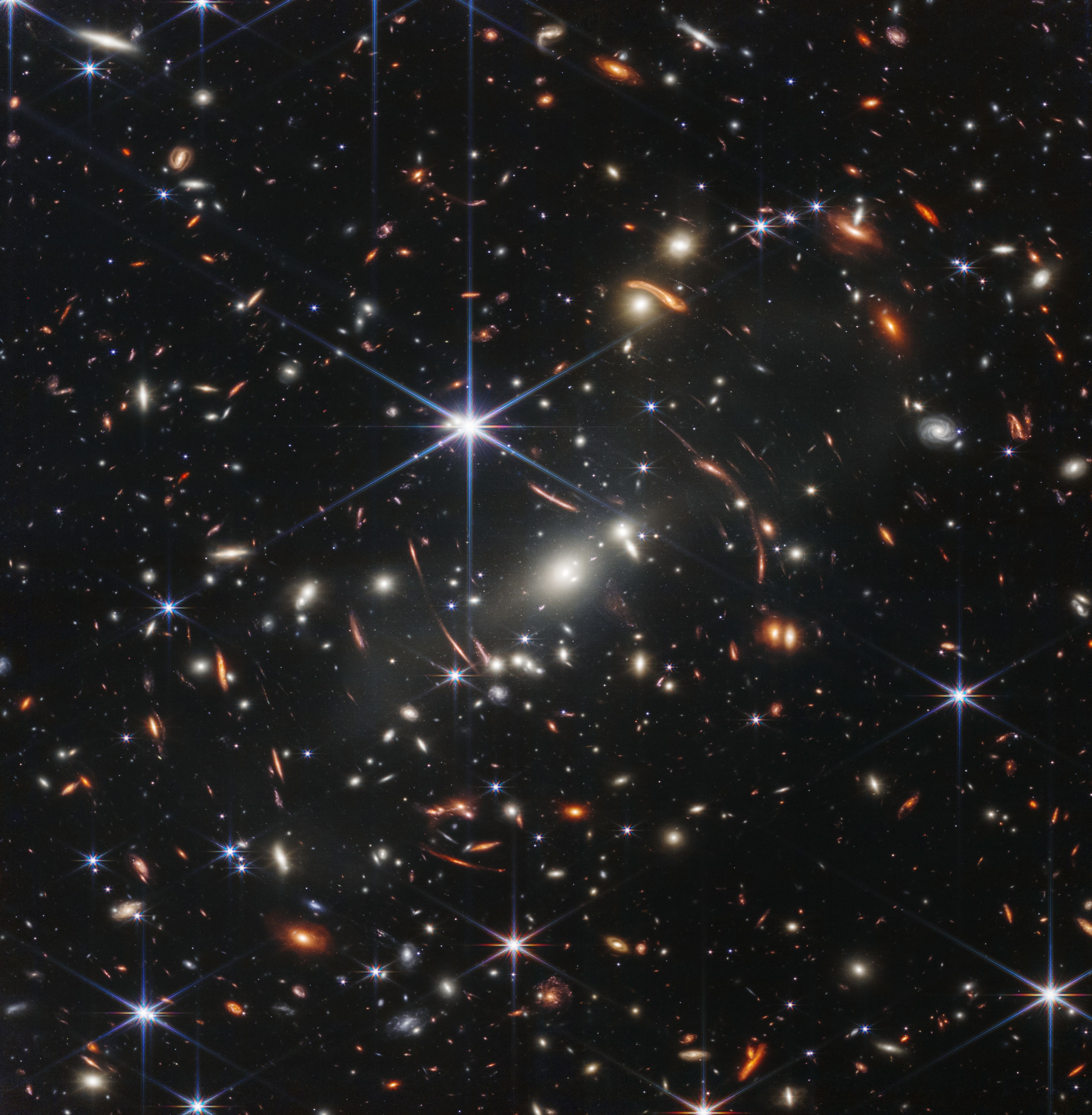 Thousands of distant galaxies and curved gravitational lensing arcs against black space