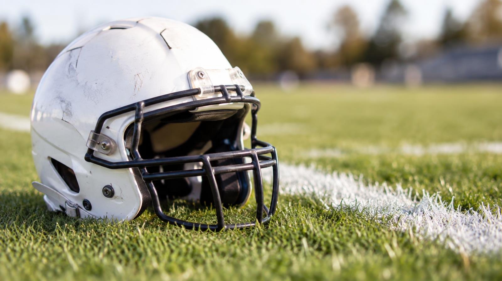 An American football helmet sitting on green grass beside a white painted yard line.