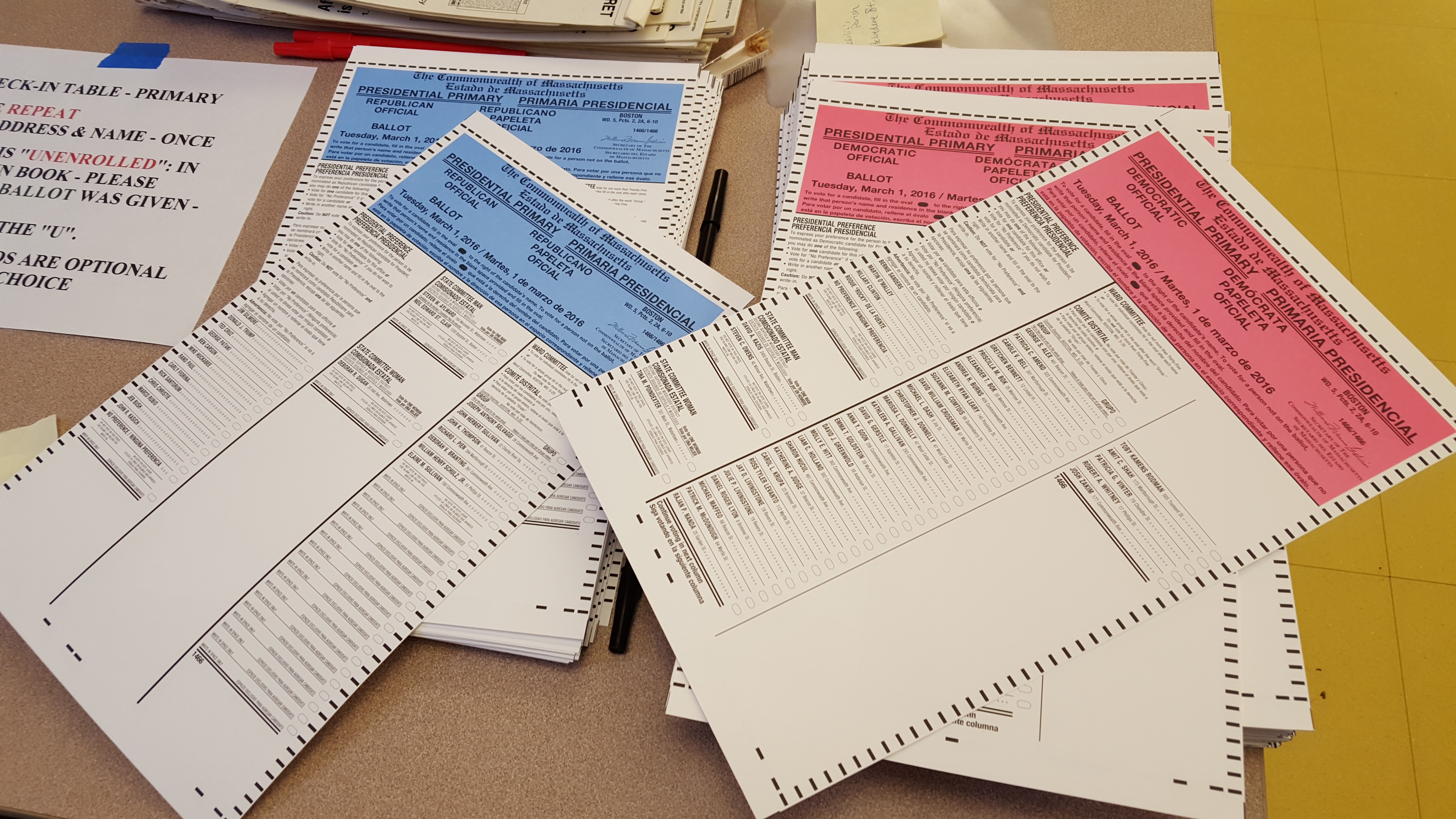 Blue, pink, and white Massachusetts primary election ballots spread across a table.