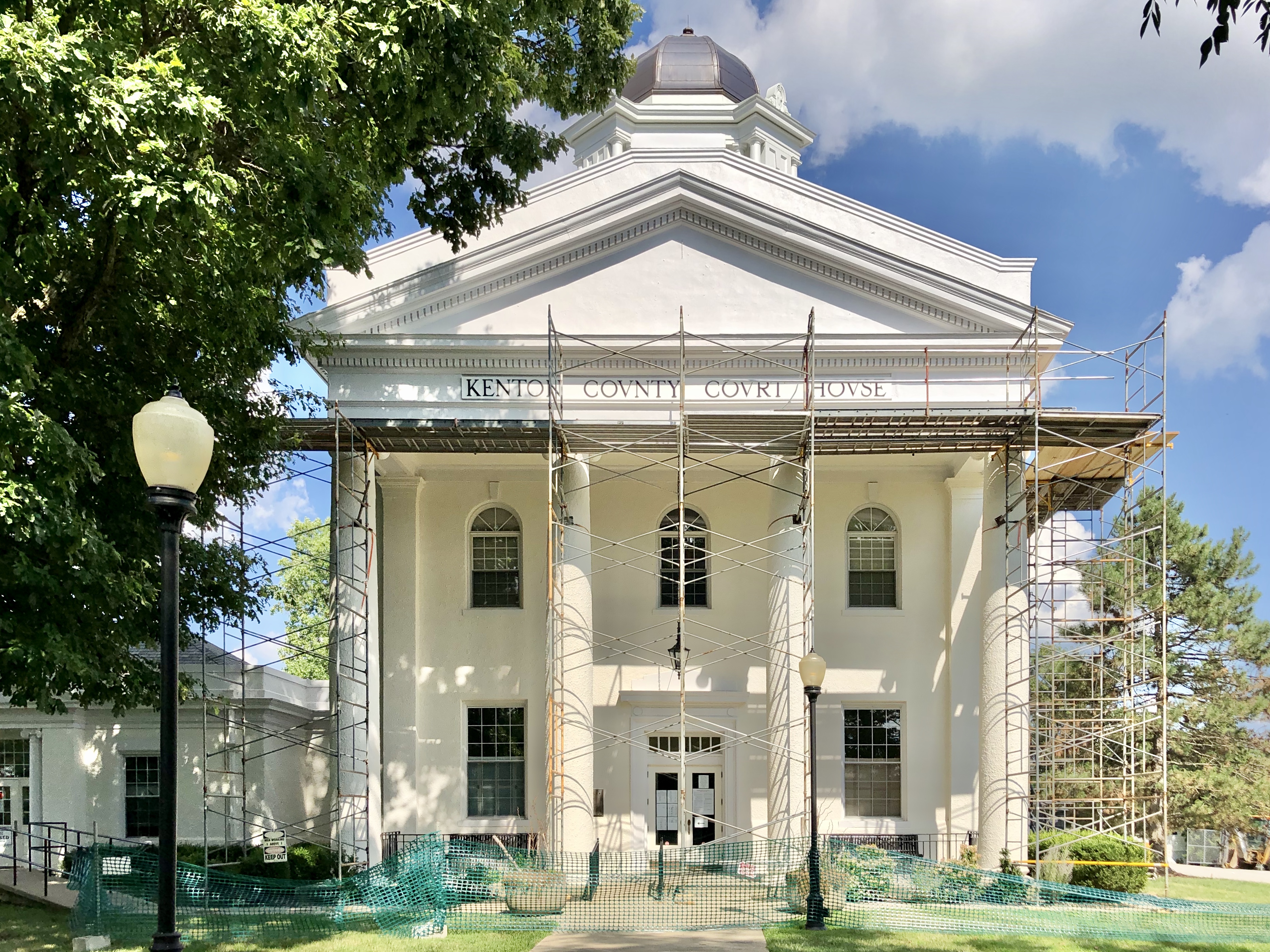 White courthouse building with neoclassical columns and a central dome, scaffolding visible on the facade.