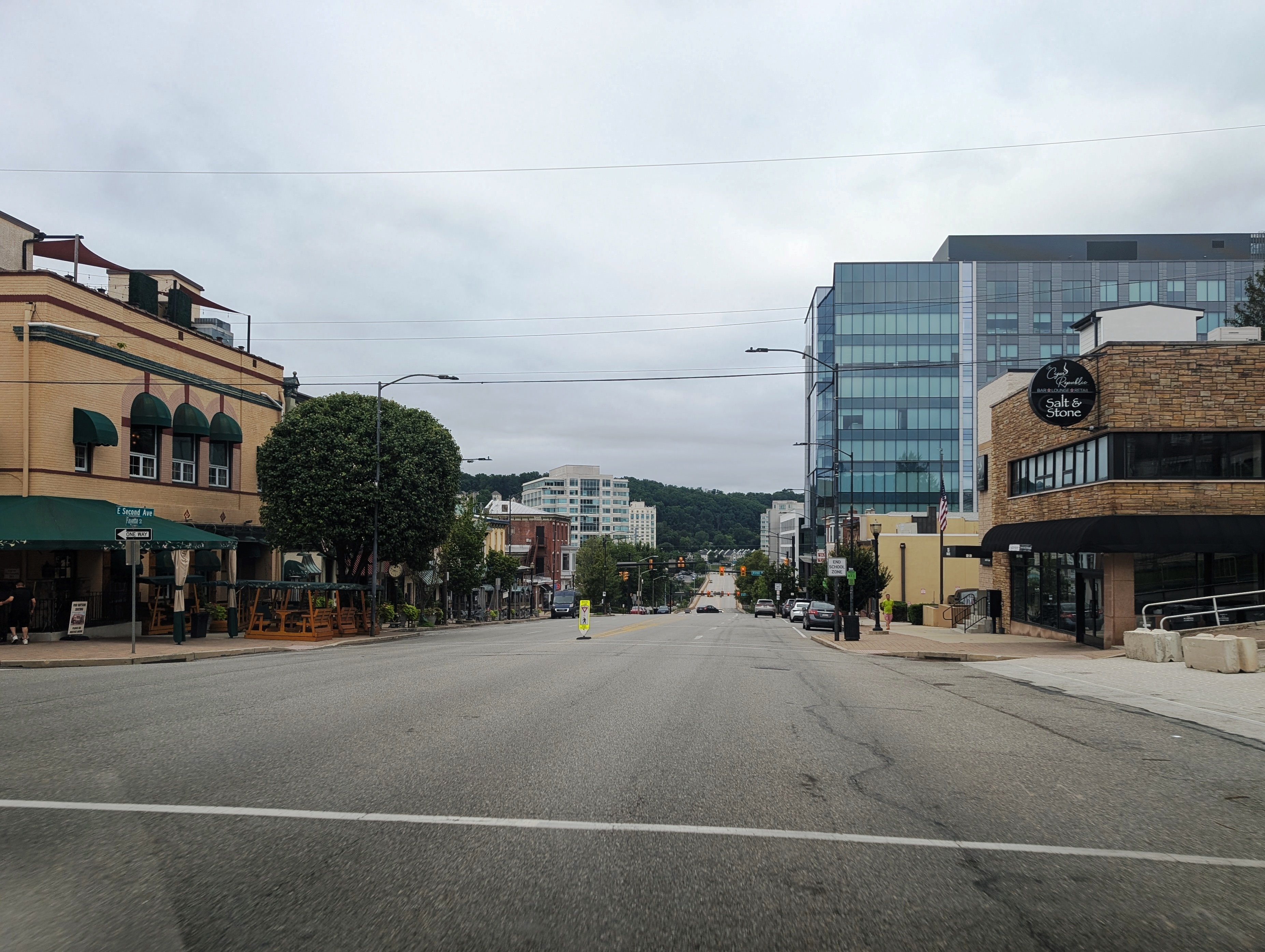 Wide urban street flanked by commercial buildings under an overcast sky.