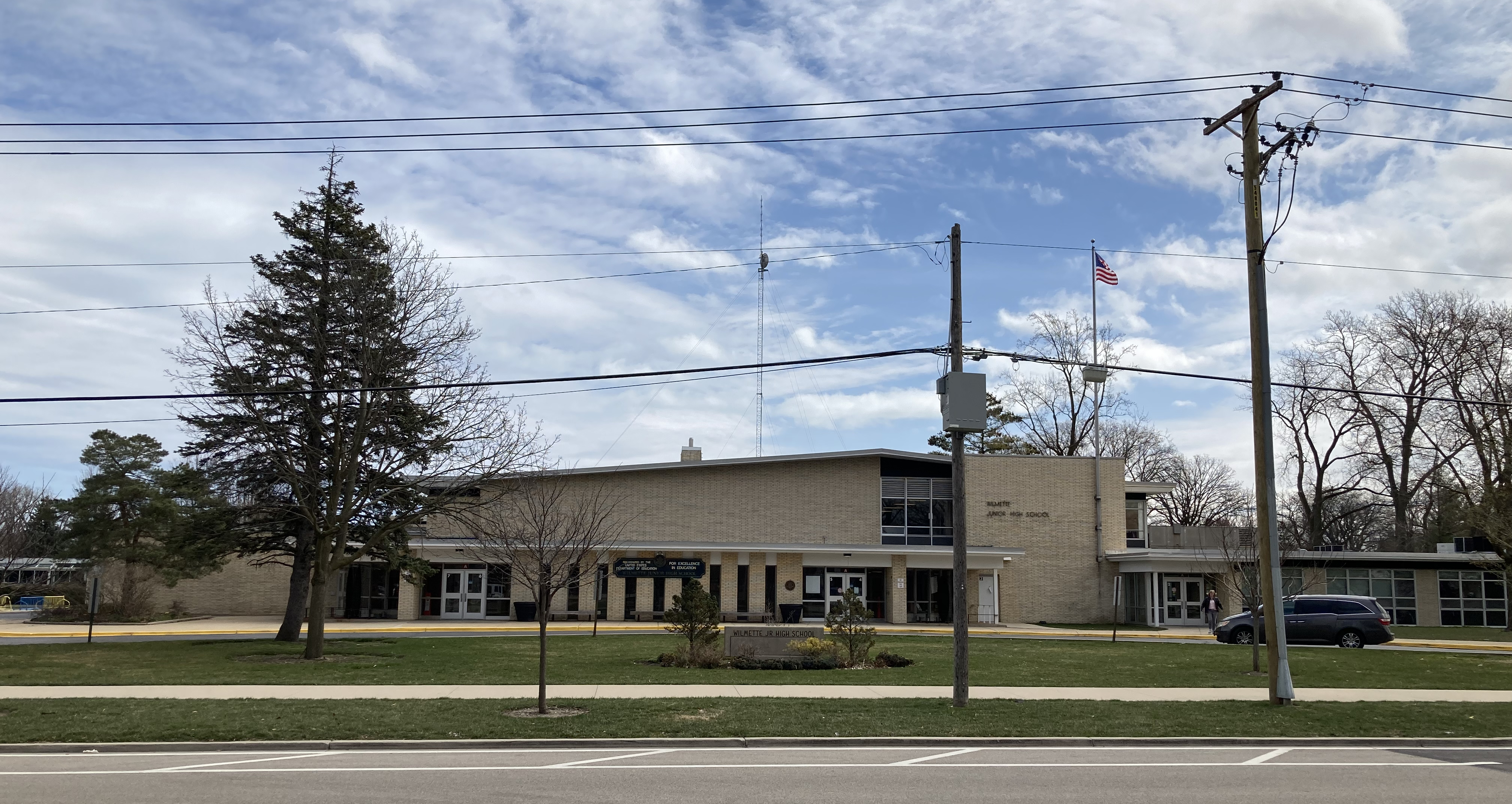 Exterior view of a brick school building with trees and a clear sky.