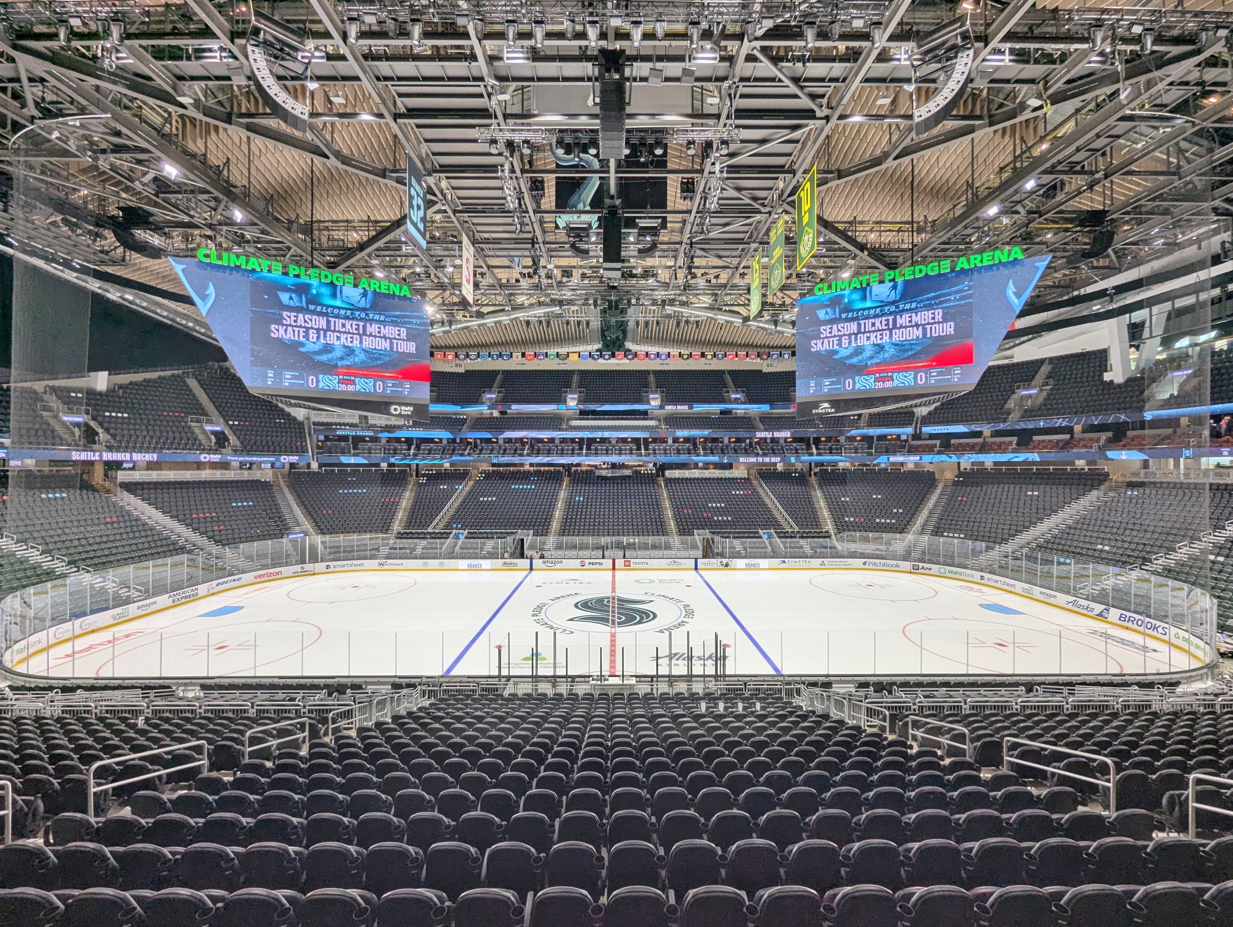 Empty indoor hockey arena viewed from center ice, showing the rink and seating bowl.