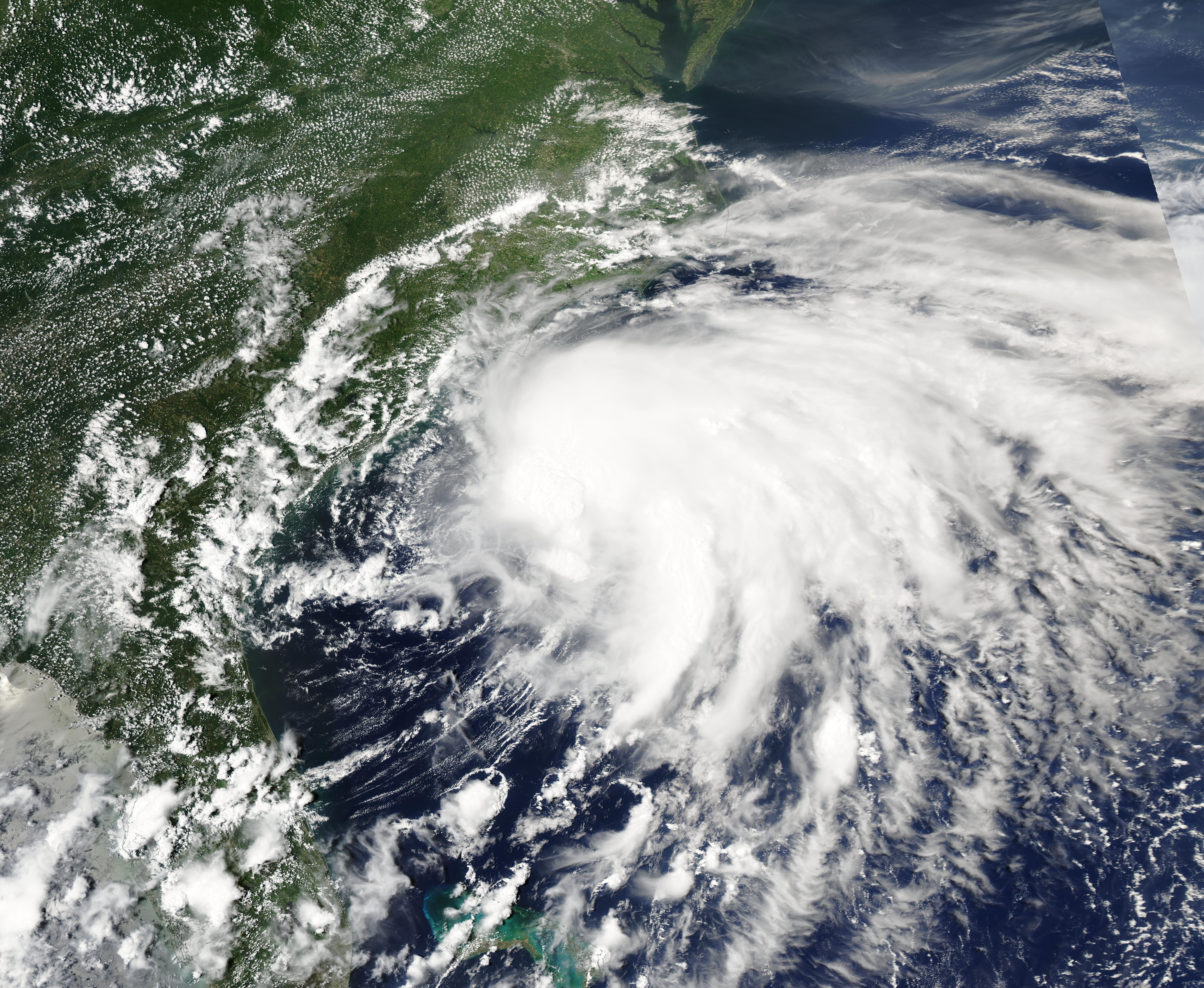 Satellite image of a tropical cyclone with spiral cloud bands approaching the southeastern United States coastline.