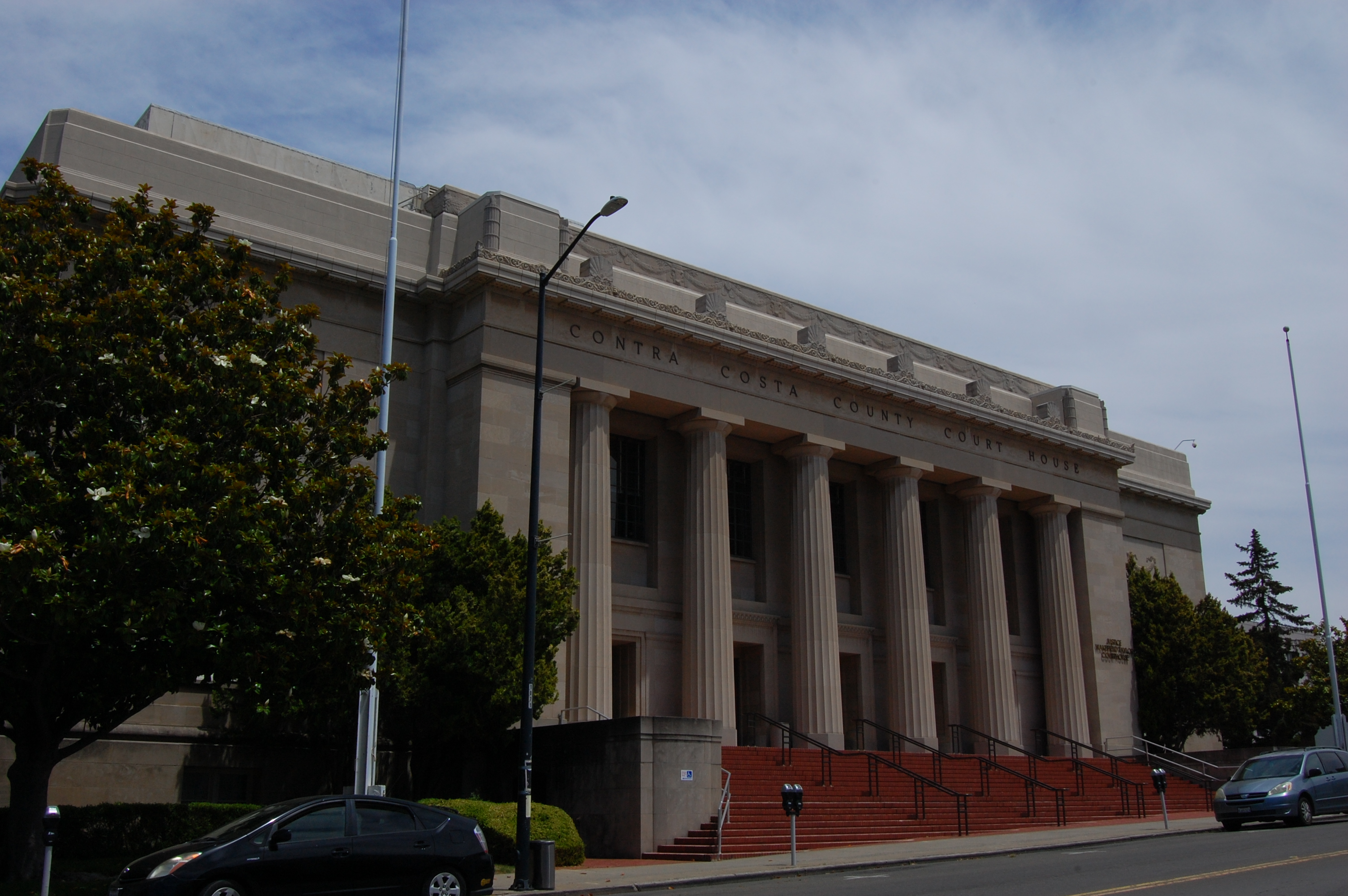 Neoclassical courthouse with tall columns and wide steps flanked by trees.