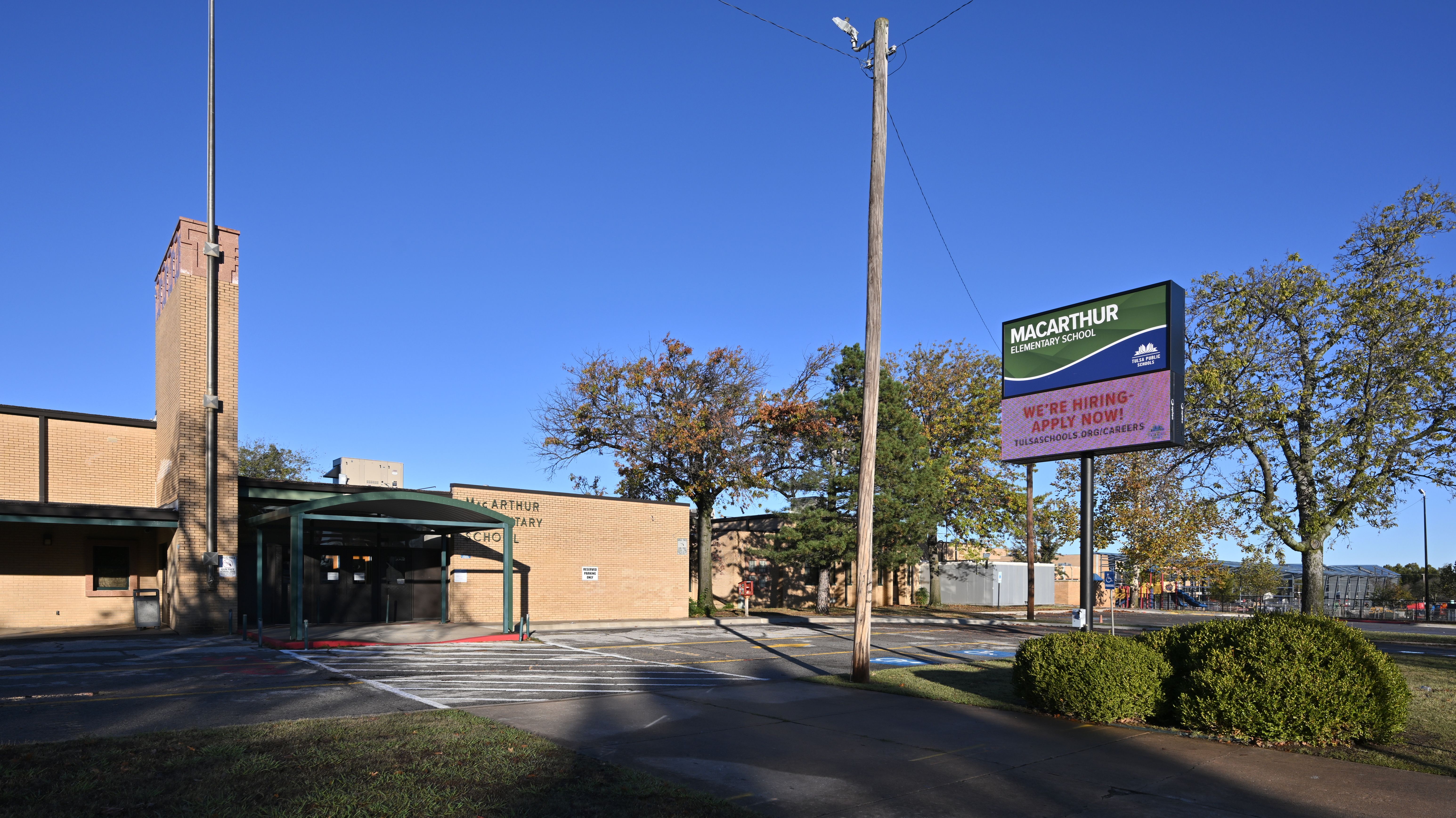 Brick elementary school building with a marquee sign under a clear blue sky.