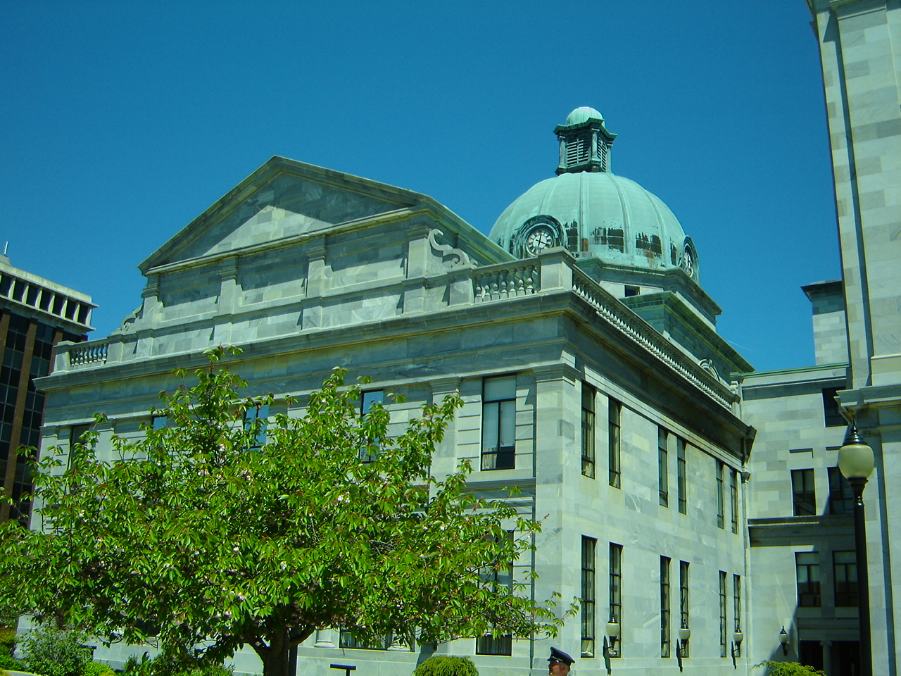 Neoclassical stone courthouse with a green copper dome under a blue sky.