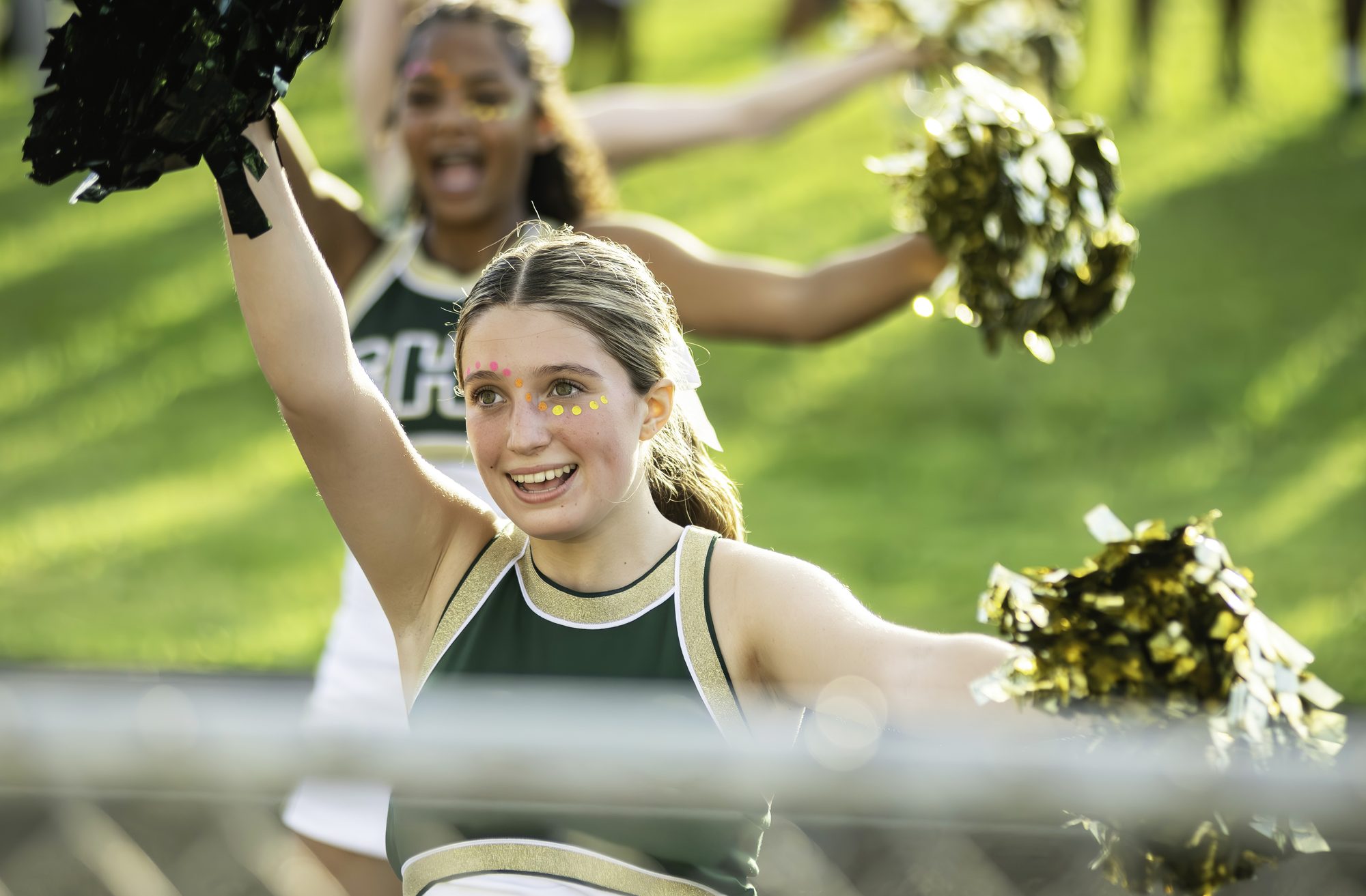 15 year old teenage girl, happy, sporty high school football cheerleader at a game cheering for her team in uniform at night