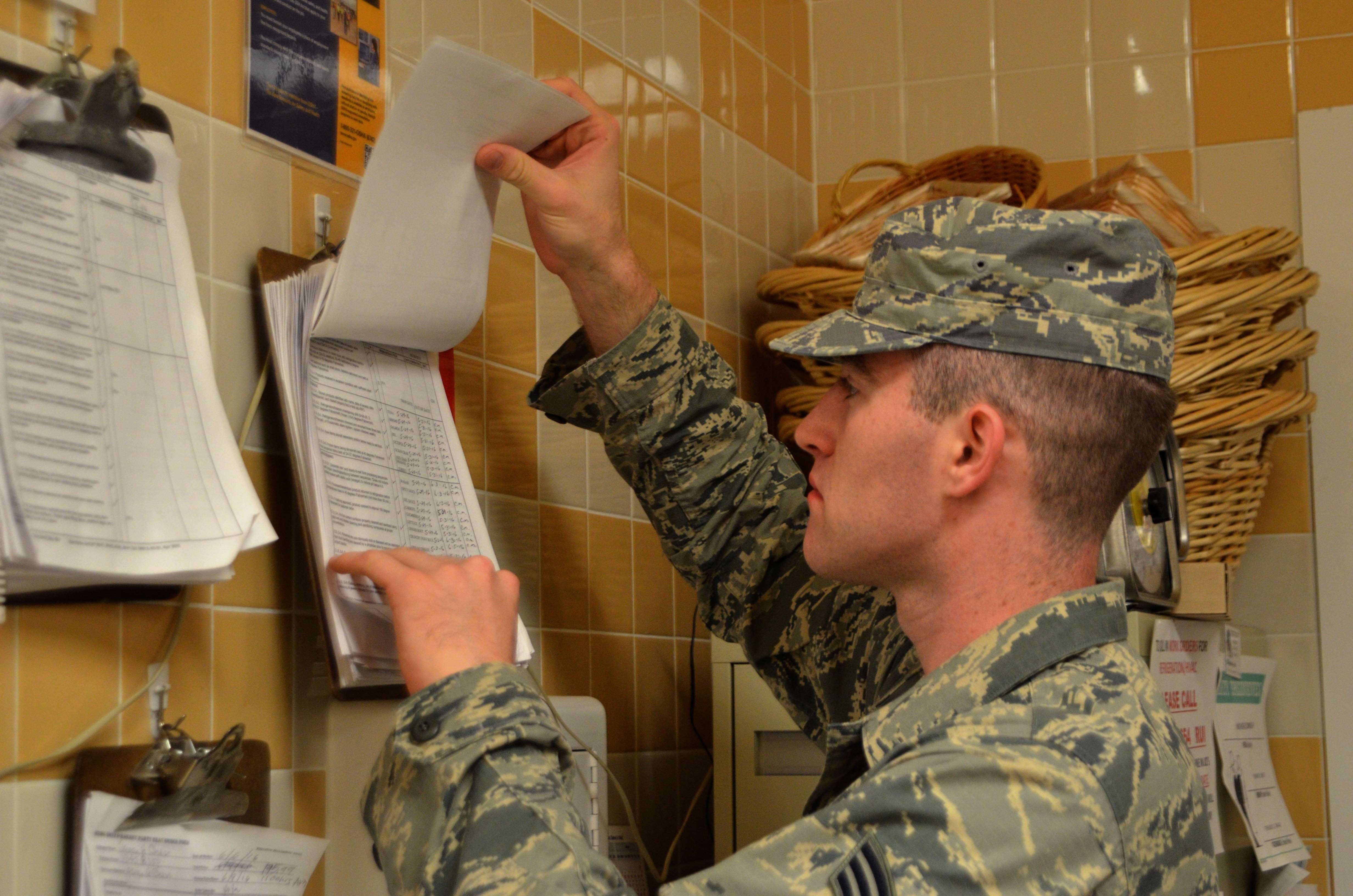 A uniformed inspector reviewing documents mounted on a tiled wall.