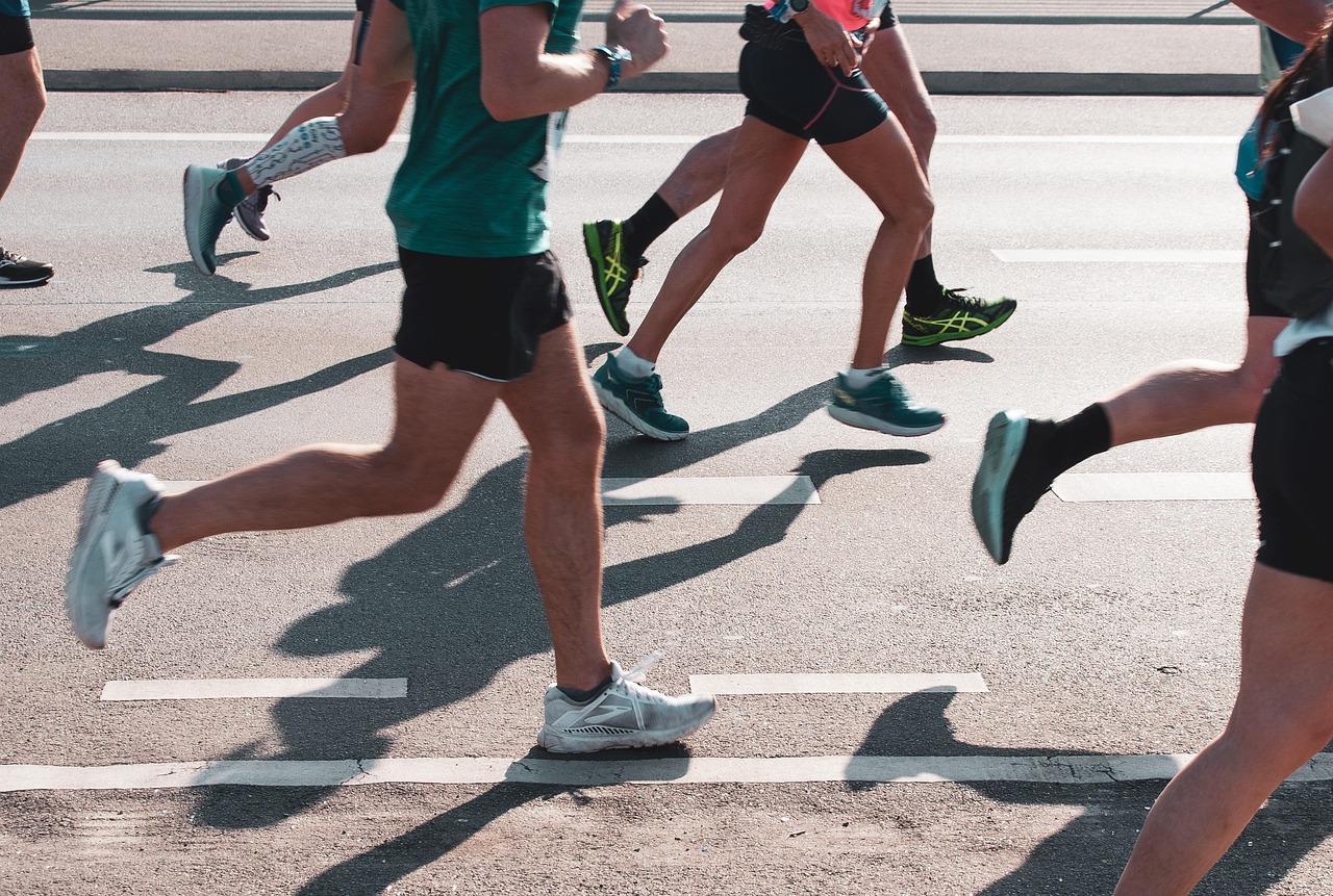 Large group of high school runners sprint across a grass field at a race start.