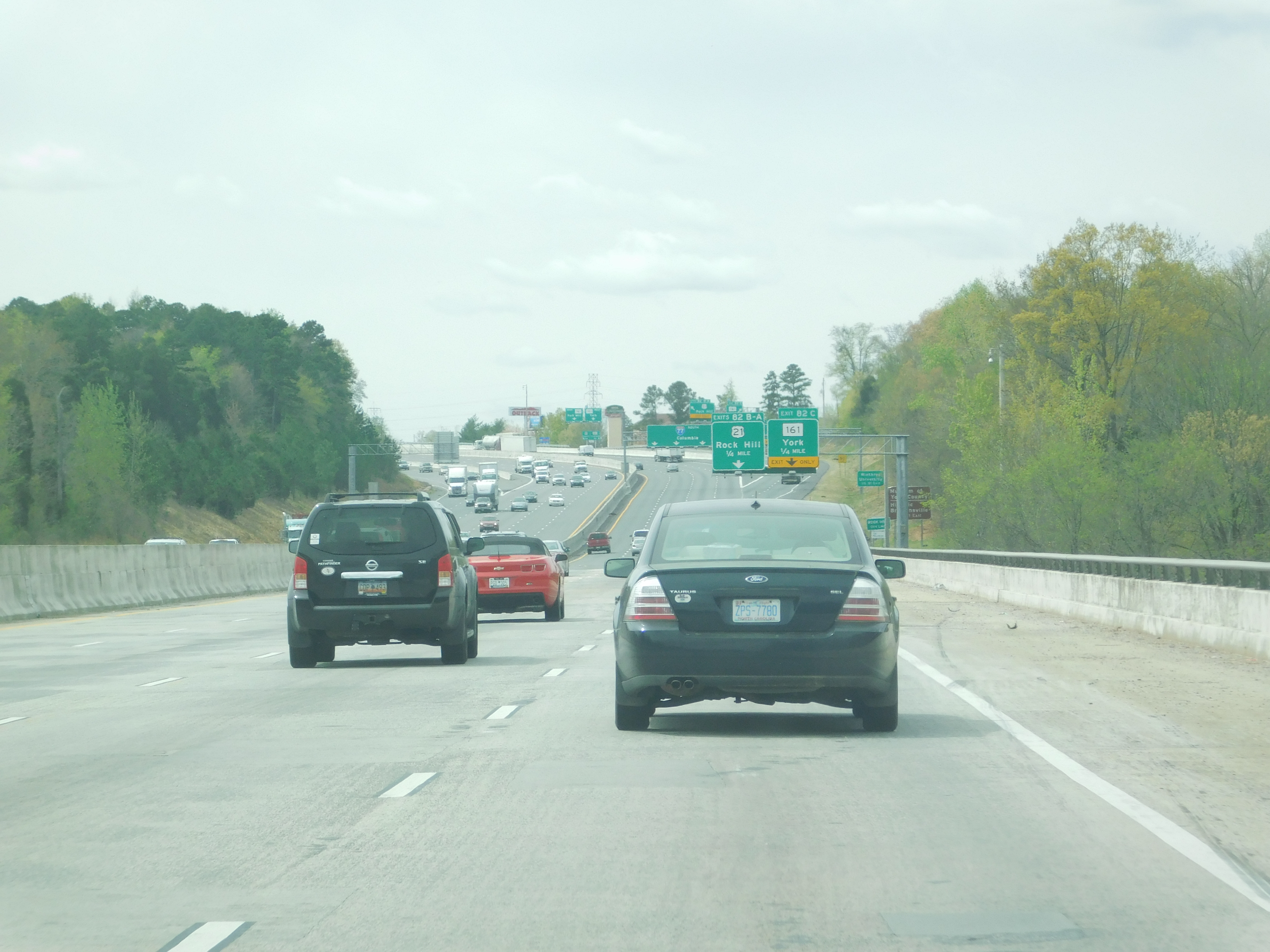 Southbound lanes of a multi-lane interstate highway with green overhead signs and light traffic.