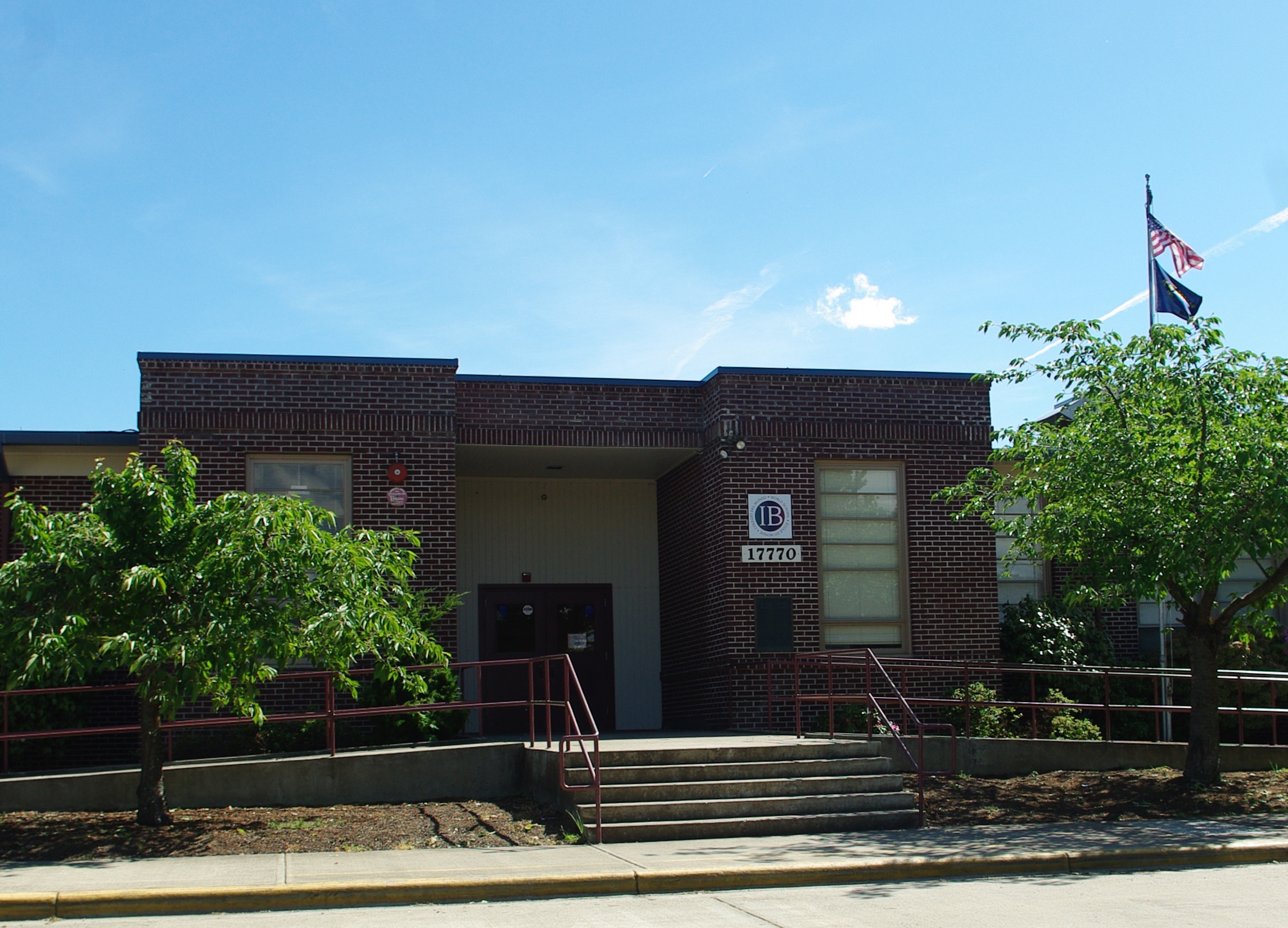 Exterior of a single-story red brick school building with a flagpole and accessible entrance ramp.