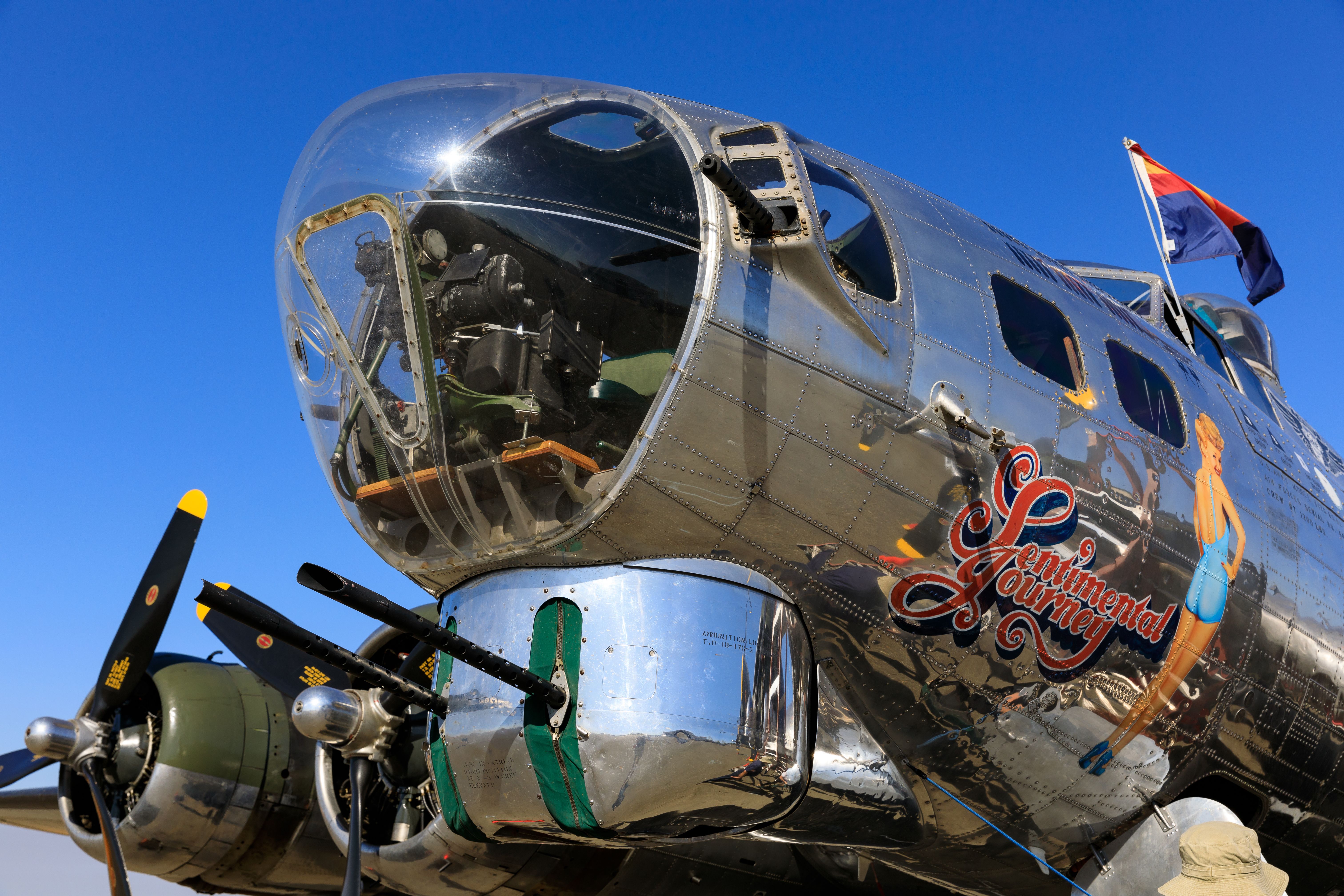 Nose of a polished aluminum B-17 bomber with glazed nose cone and painted pin-up art.