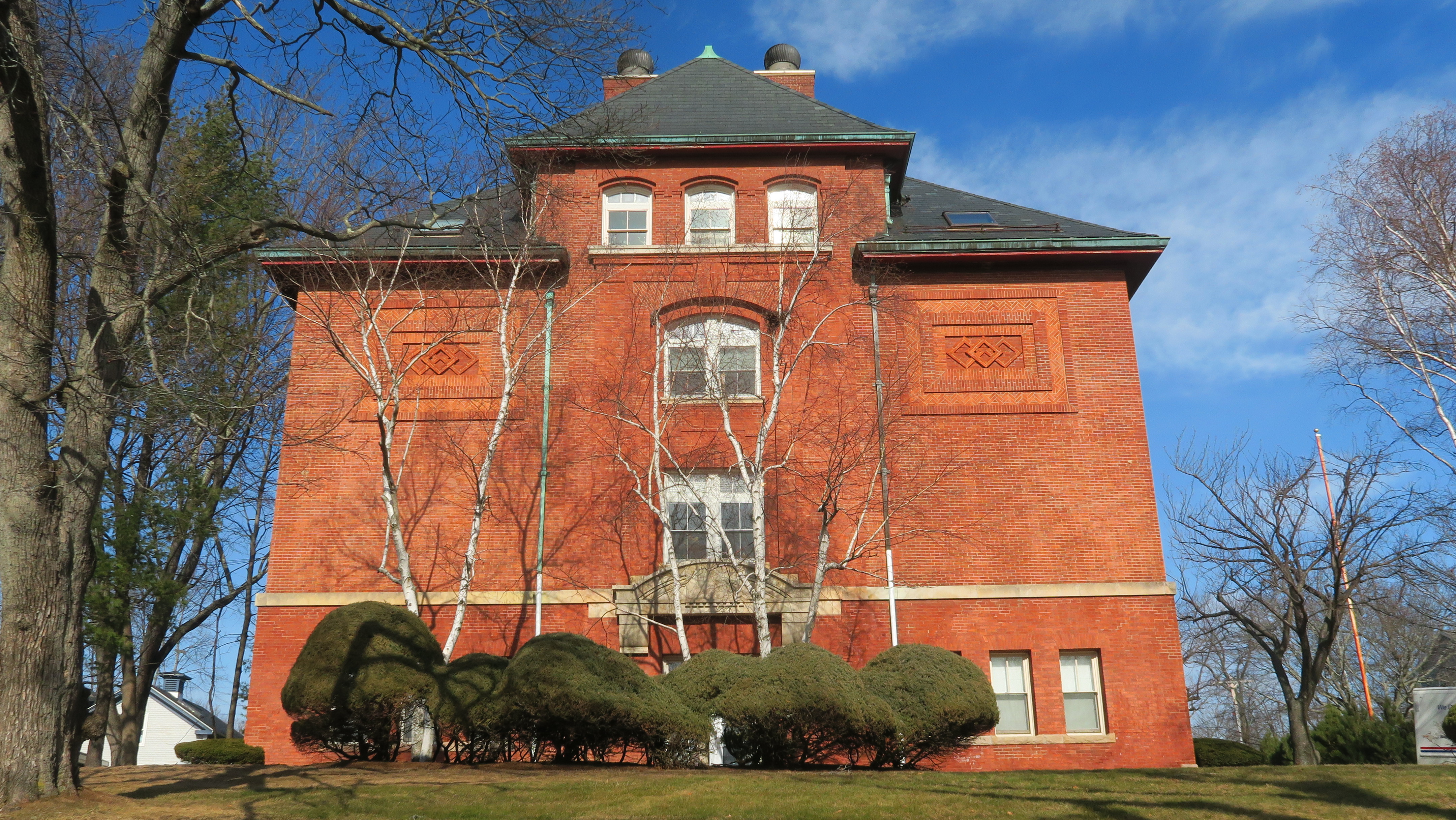 Red-brick Victorian-era elementary school building with bare trees in the foreground.