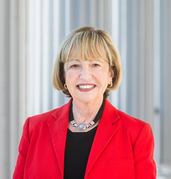 Woman with short blonde hair in a red blazer smiling in a professional portrait.