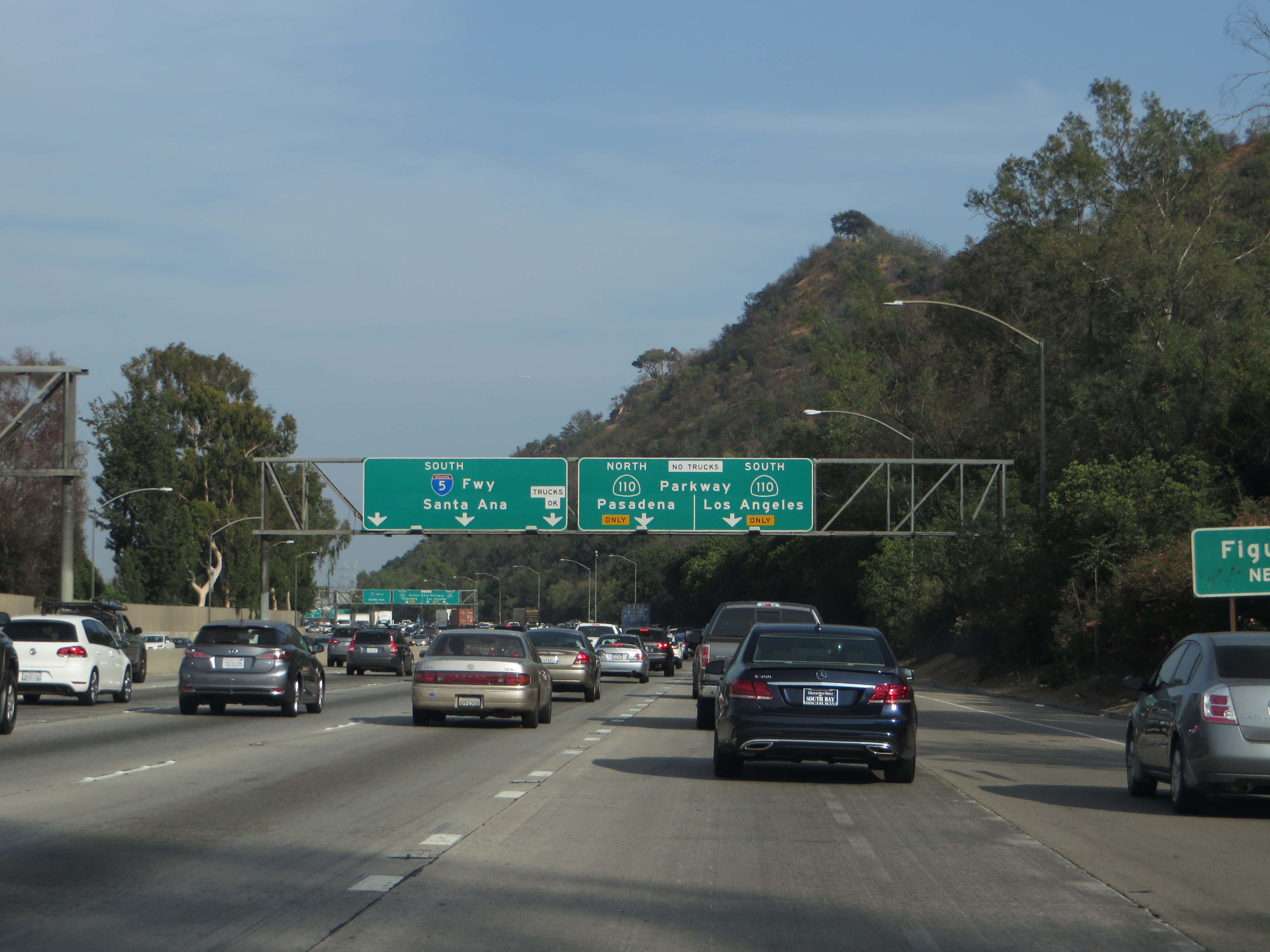 Multi-lane freeway with heavy traffic and overhead green highway directional signs.