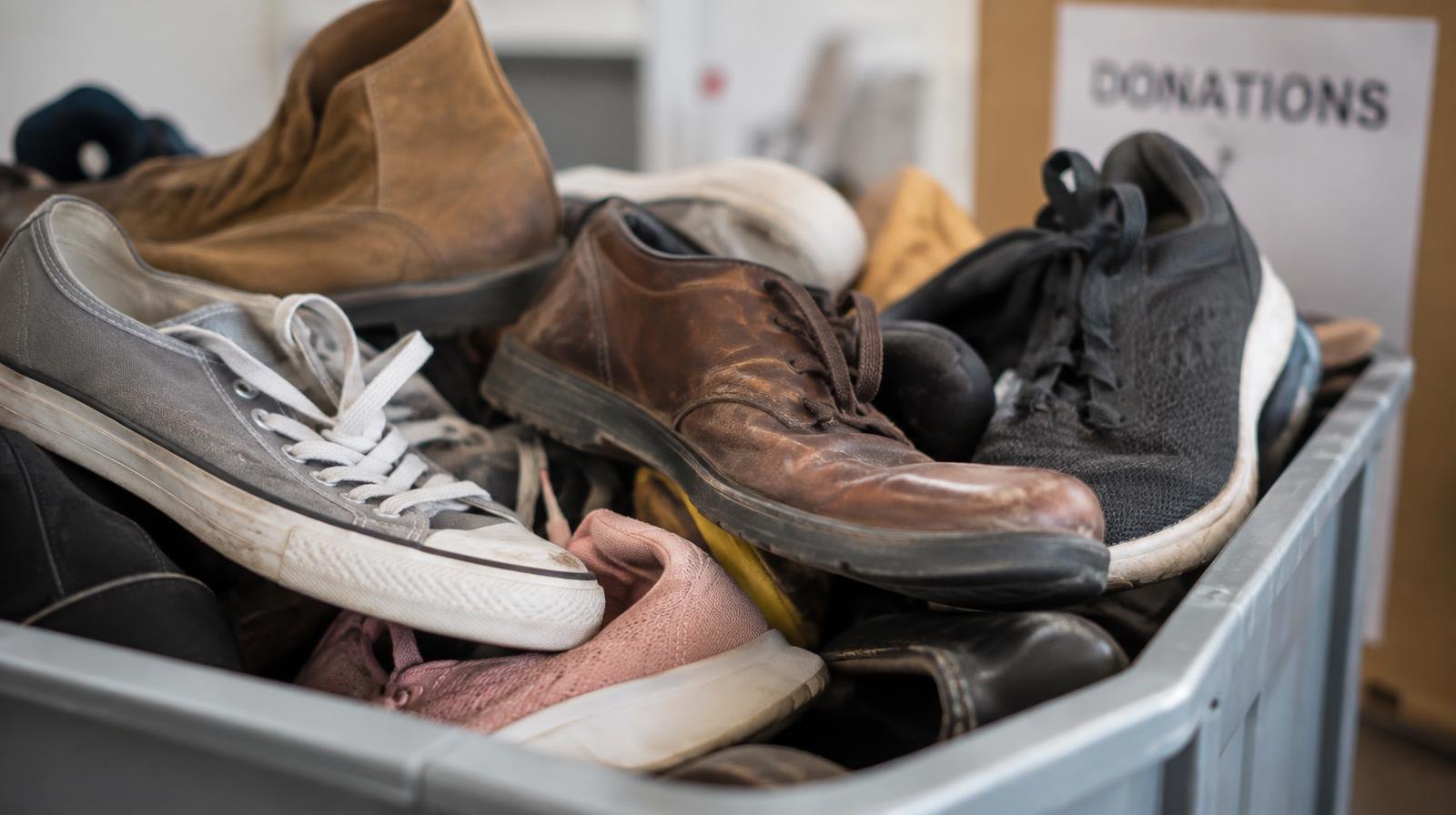 Assorted gently worn shoes of various colors piled together in a donation bin.