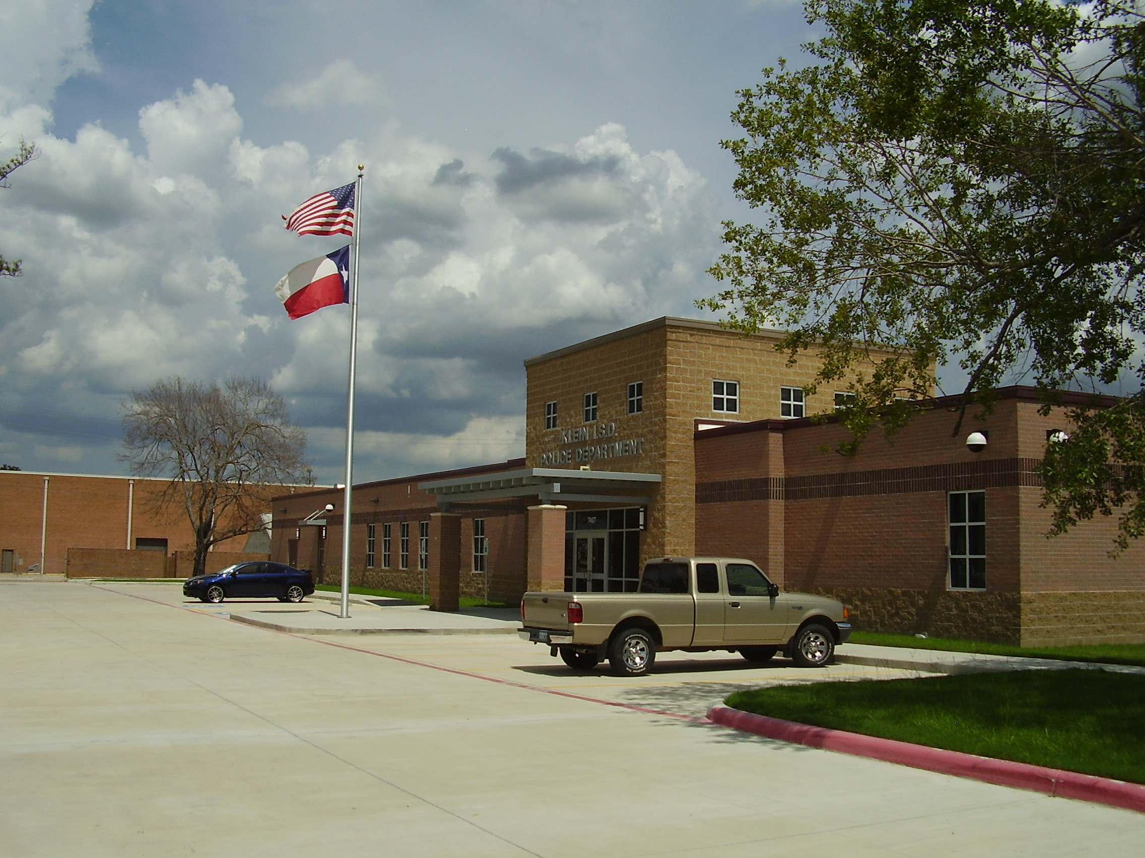 Brick institutional building with American and Texas flags on a flagpole in front.