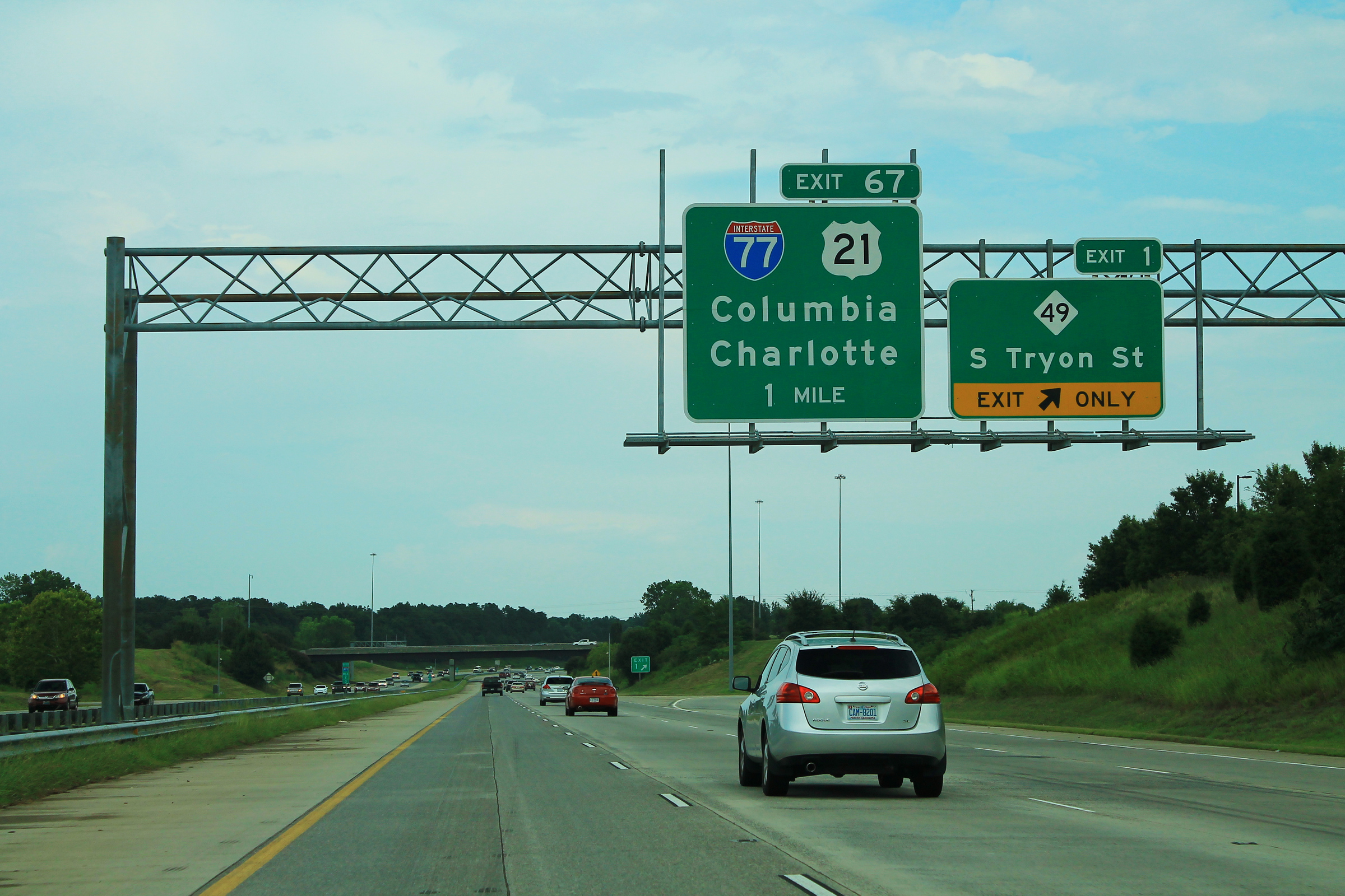 Multi-lane highway with green overhead signs pointing toward I-77 North and Charlotte.